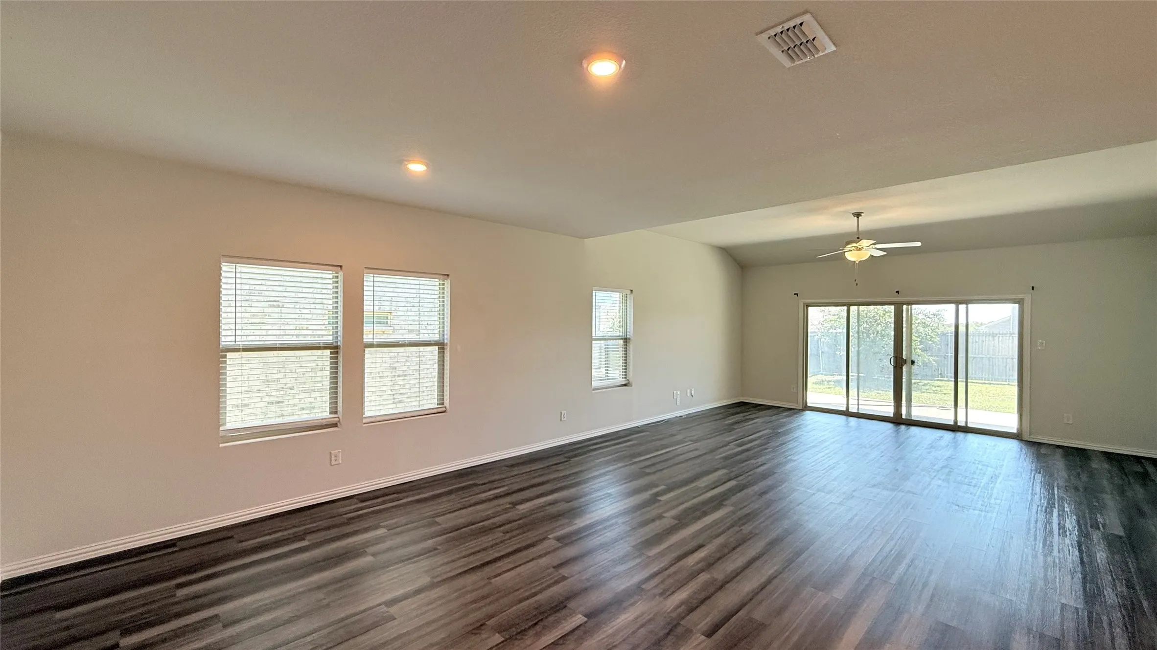 Spacious interior featuring wood-finish flooring, vaulted ceiling, recessed lighting, and a ceiling fan