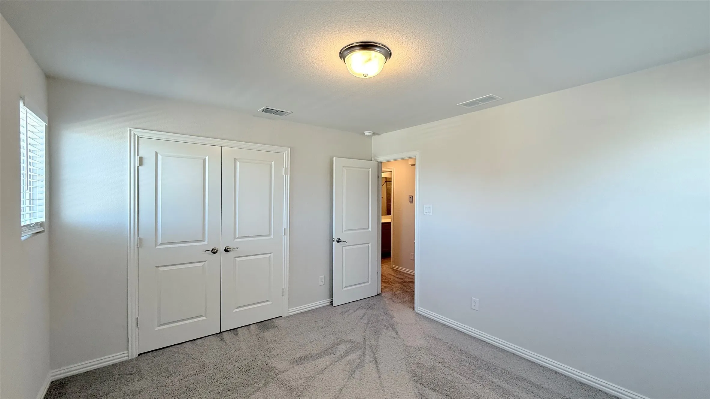 Interior room with soft gray carpeting, white painted walls, and a window with white blinds