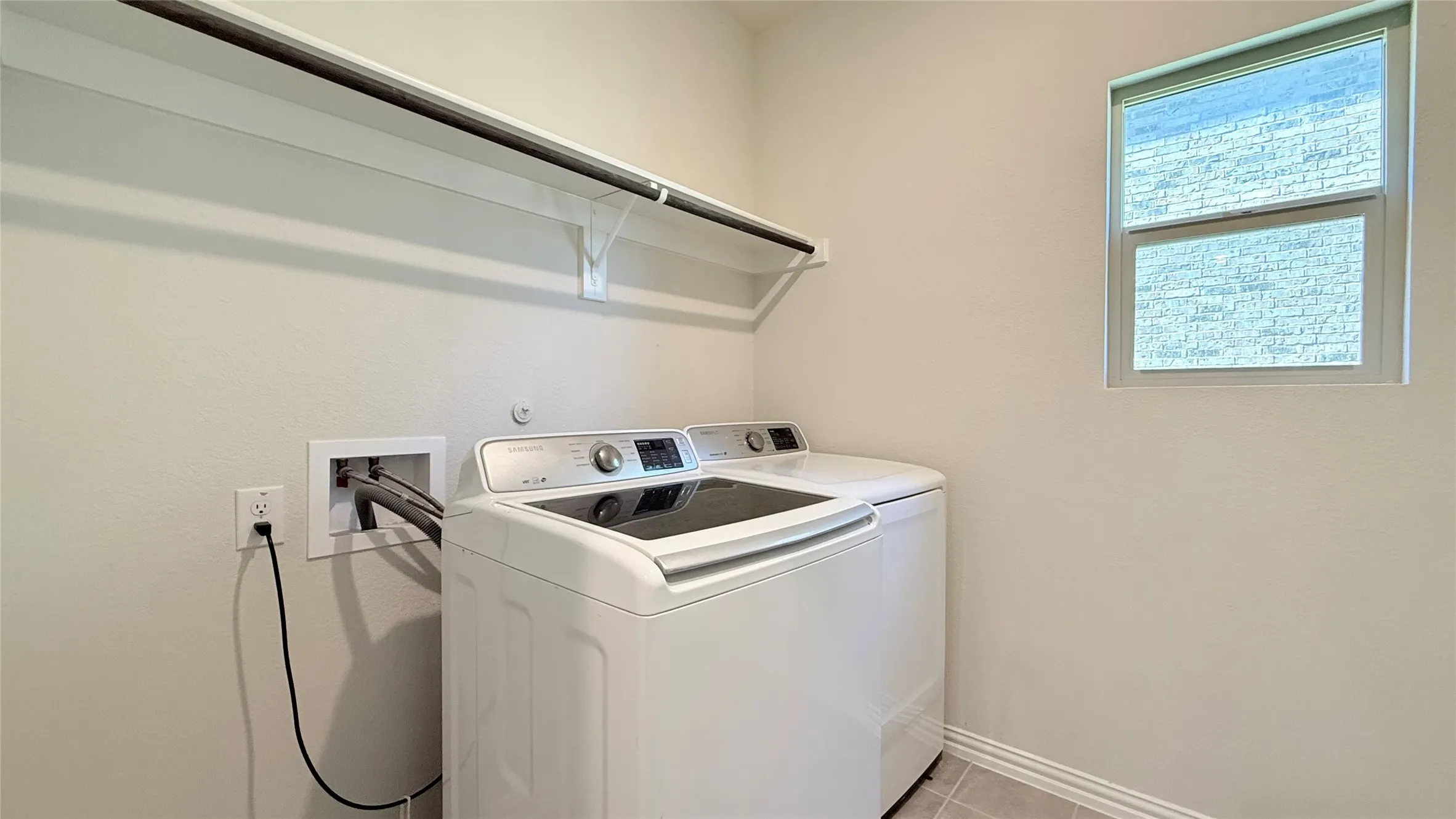 Laundry area with tile flooring, a single window, and a built-in shelf with a hanging rod