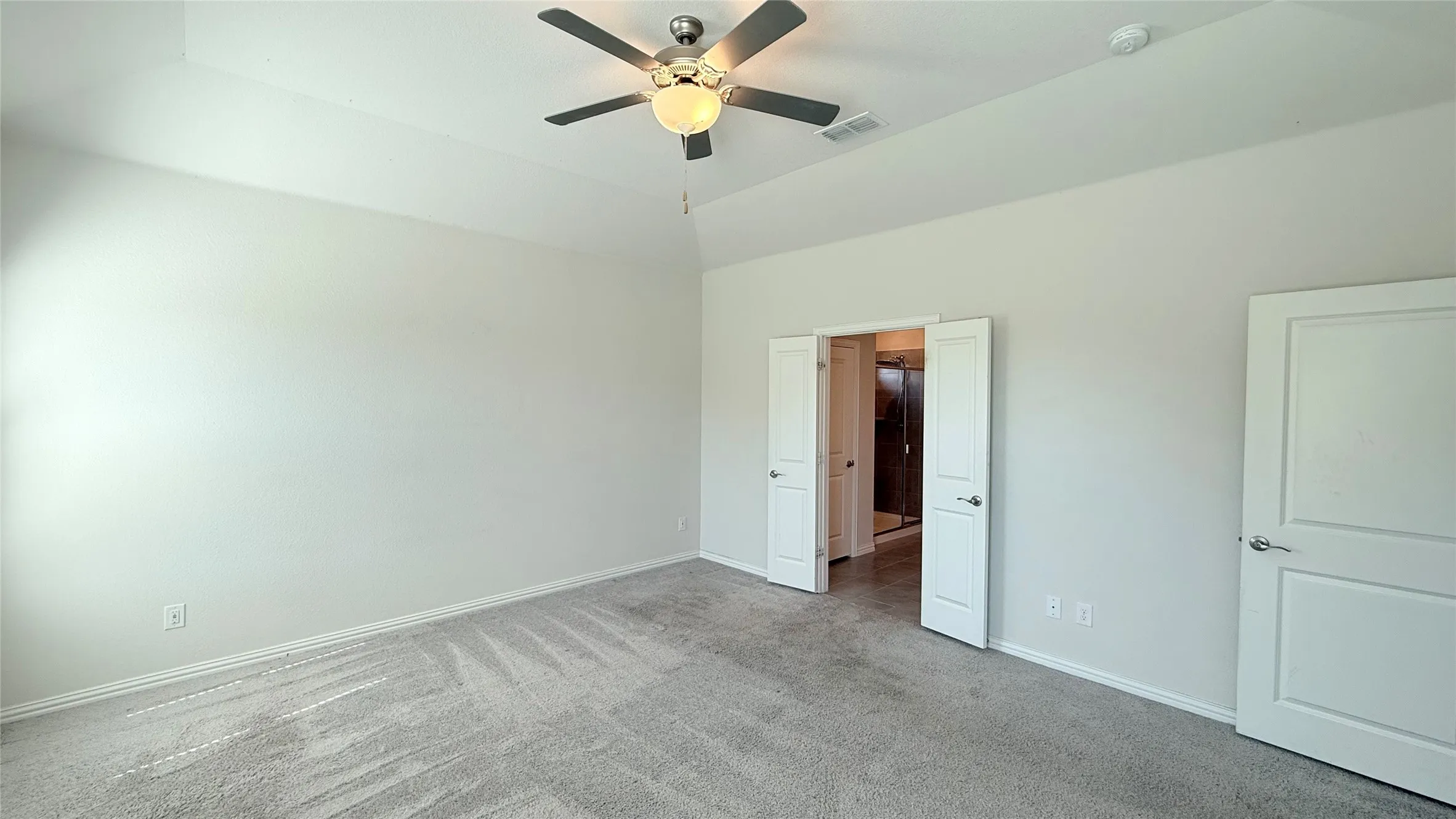 Vaulted ceiling with a contemporary ceiling fan, light gray carpeting, and white paneled doors