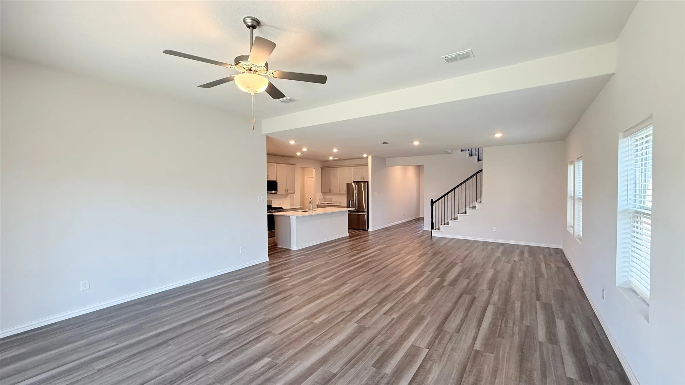 Open-concept living area with wood-finish flooring, a contemporary ceiling fan, and recessed lighting