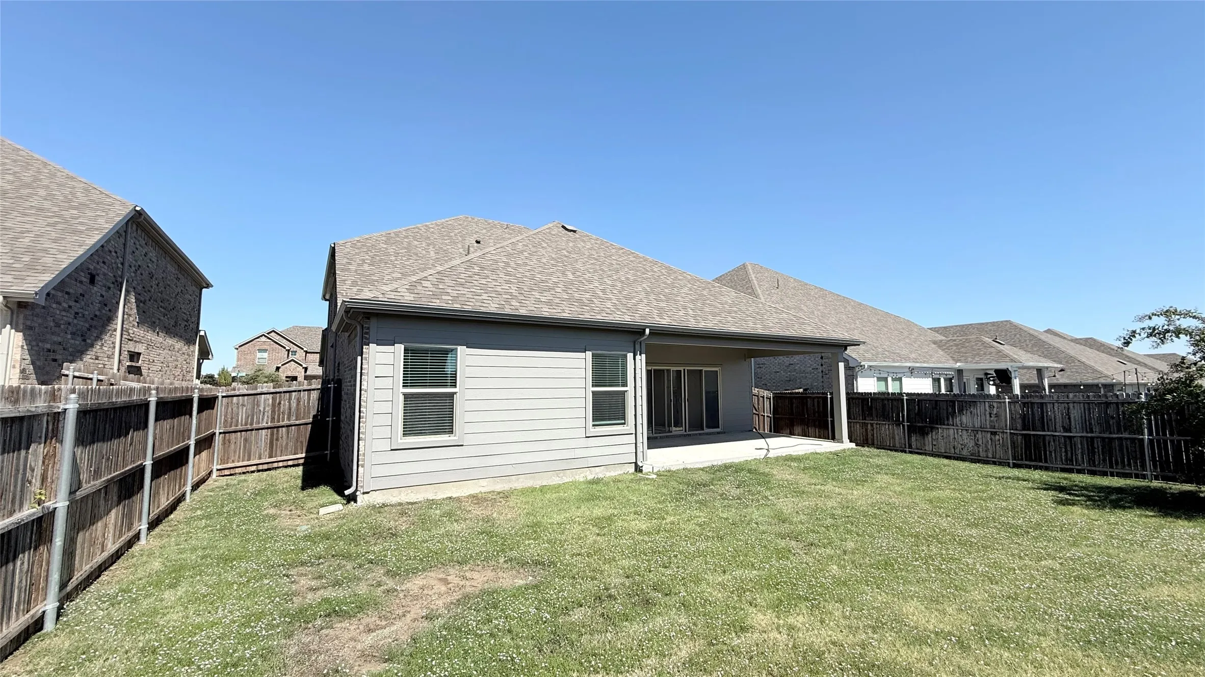 Expansive green space with a wood privacy fence, covered patio, and dual-pane windows