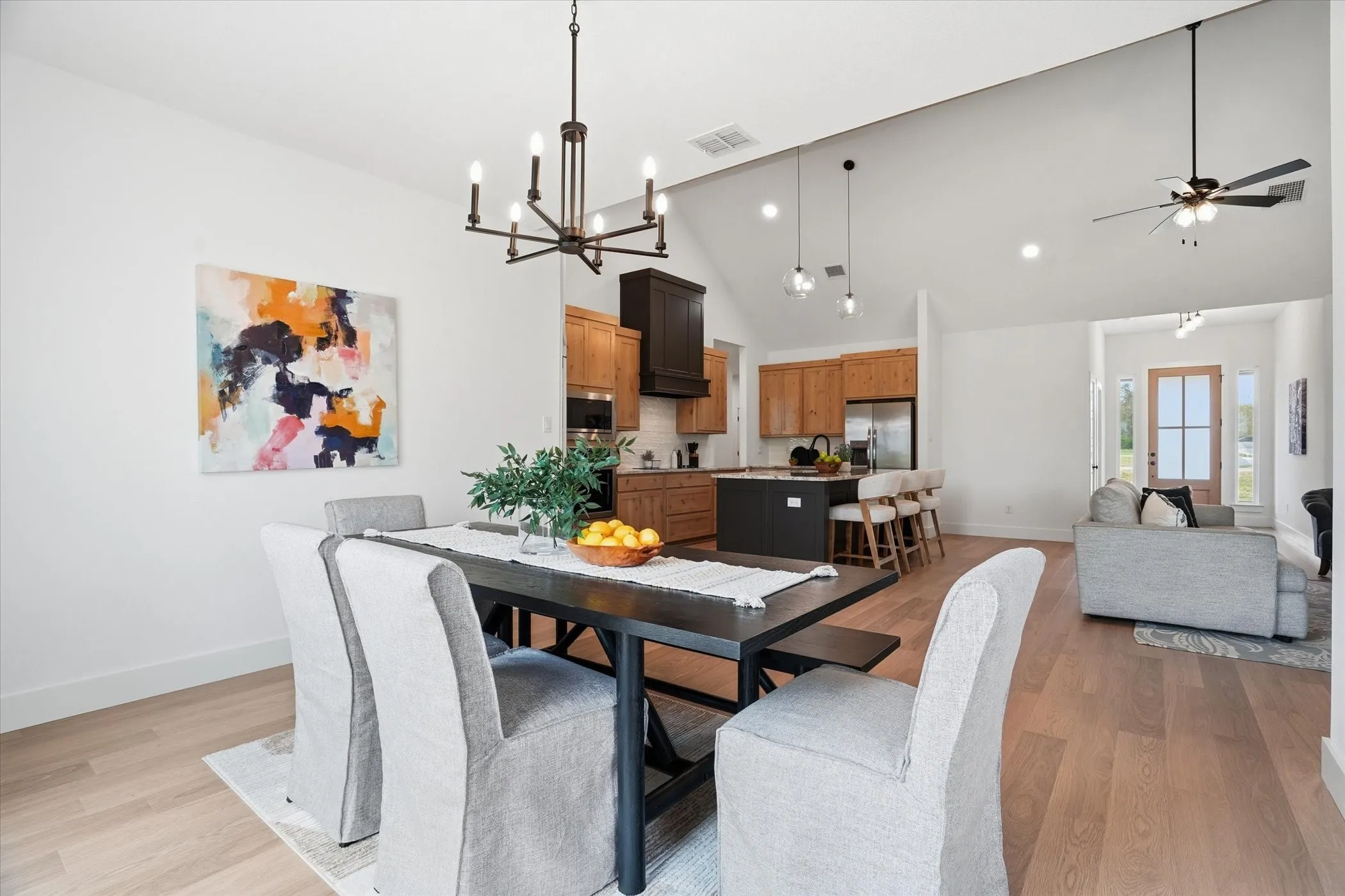 Open-concept living area featuring vaulted ceilings, wood-finish flooring, a modern chandelier, and recessed lighting