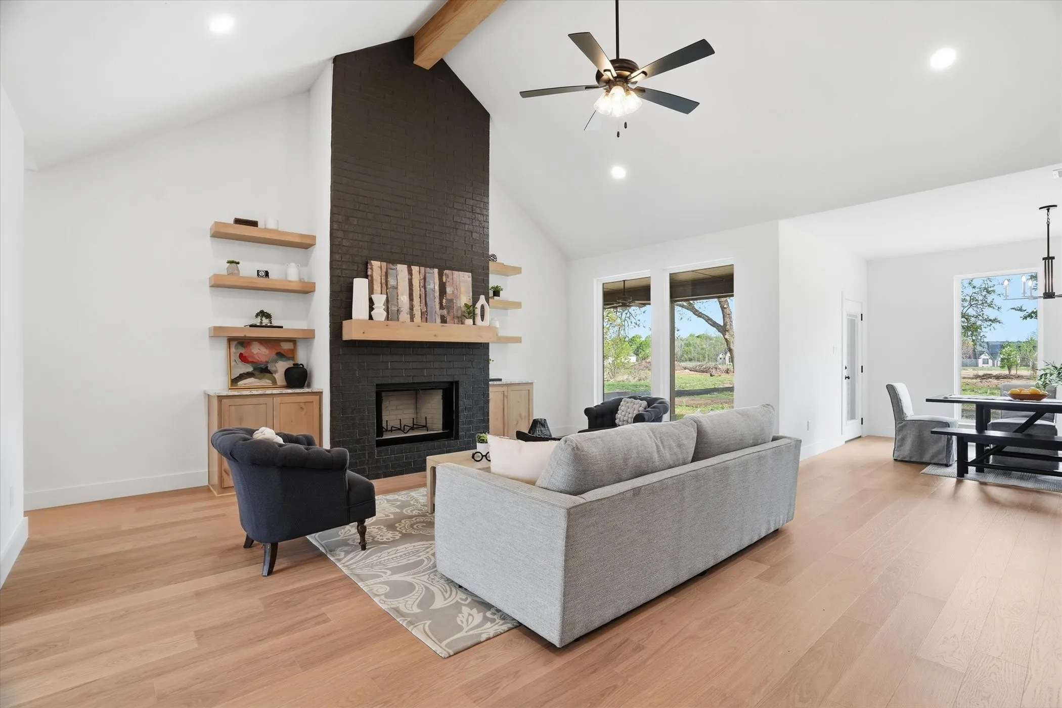 Vaulted ceilings with an exposed wood beam, black brick fireplace with a wood mantle, wood-finish flooring, and recessed lighting