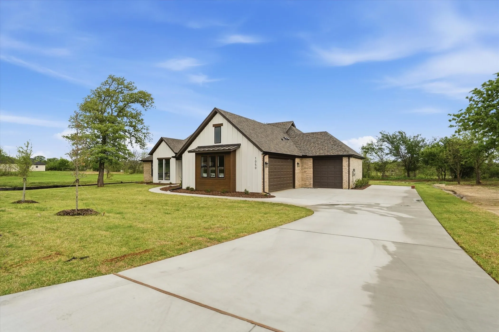 Modern farmhouse residence featuring a composite exterior with brown and cream tones, peaked gable roofline, and arched entryway