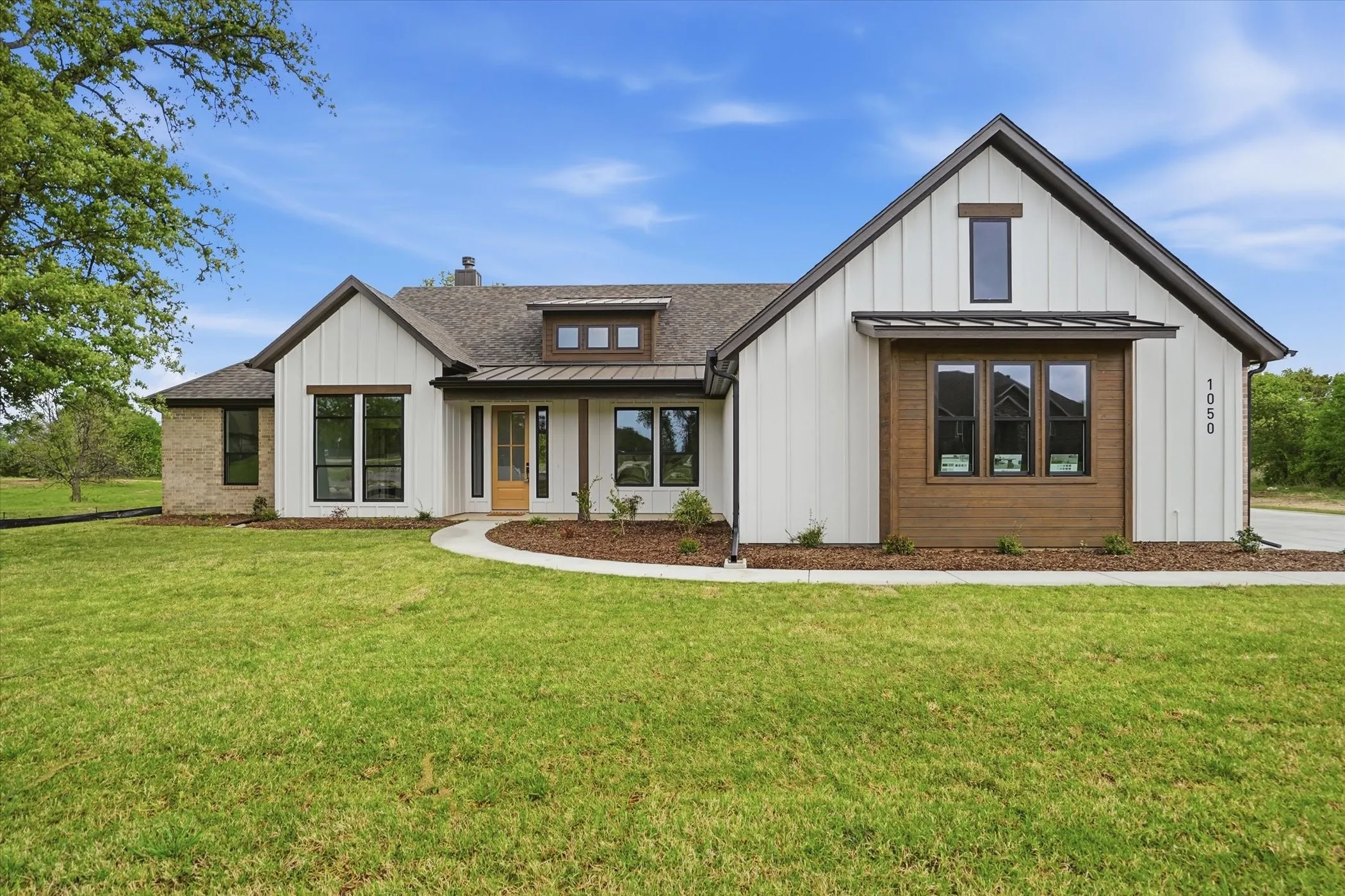 Contemporary farmhouse exterior featuring vertical white siding and brick accents