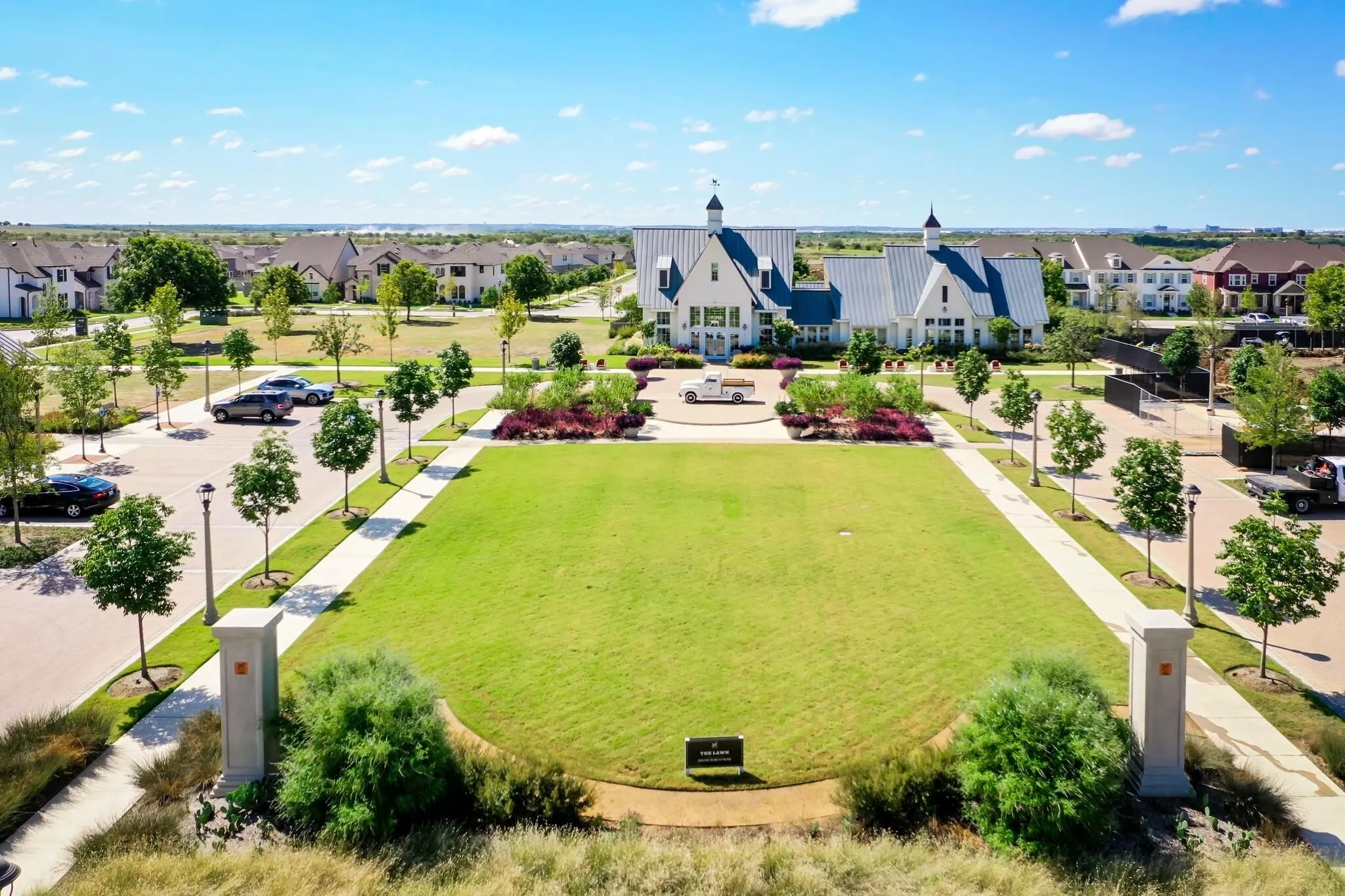 Expansive green space with manicured lawn and mature trees, surrounded by residential properties