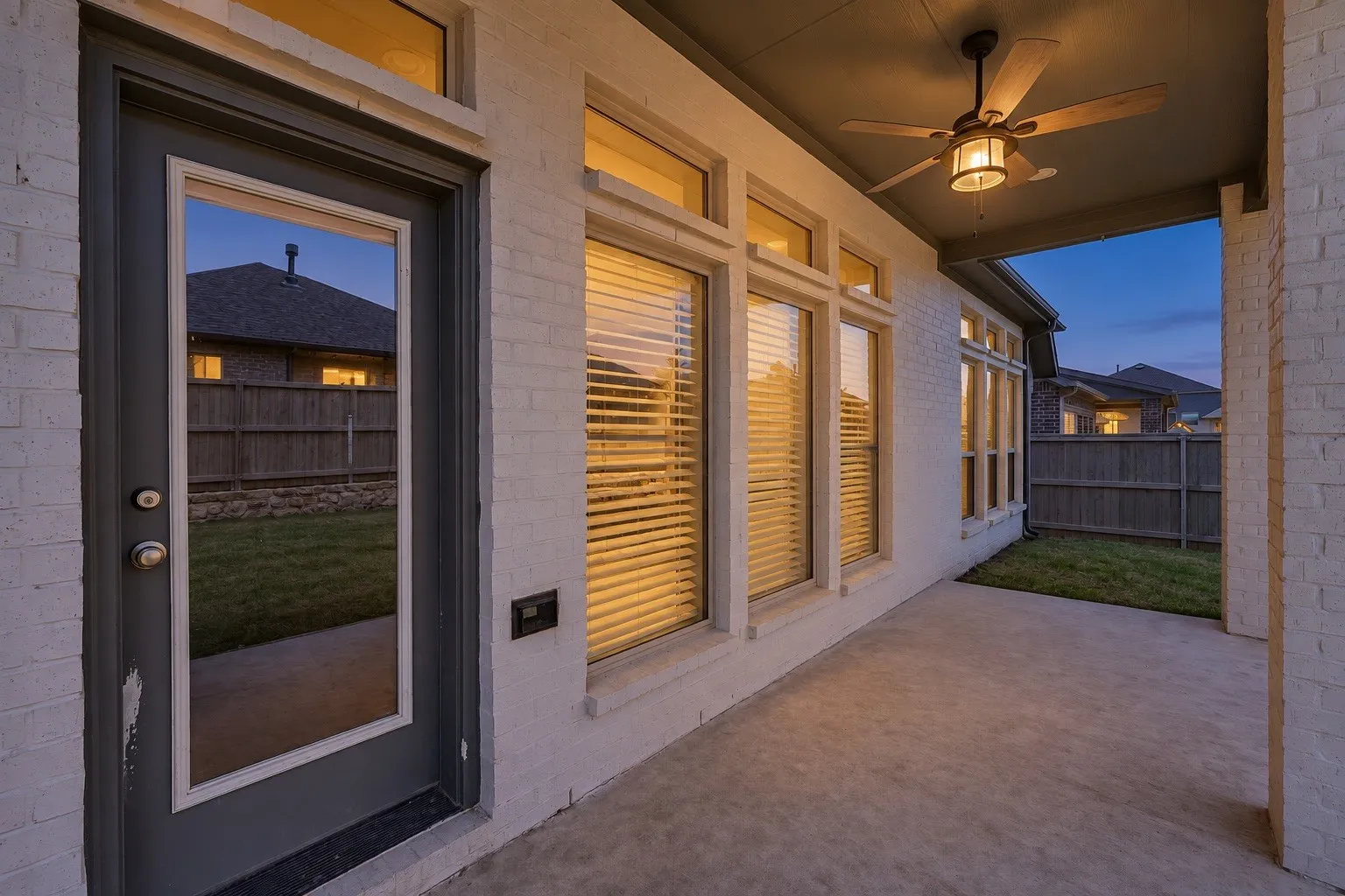 Covered patio with a ceiling fan, light fixture, and concrete flooring