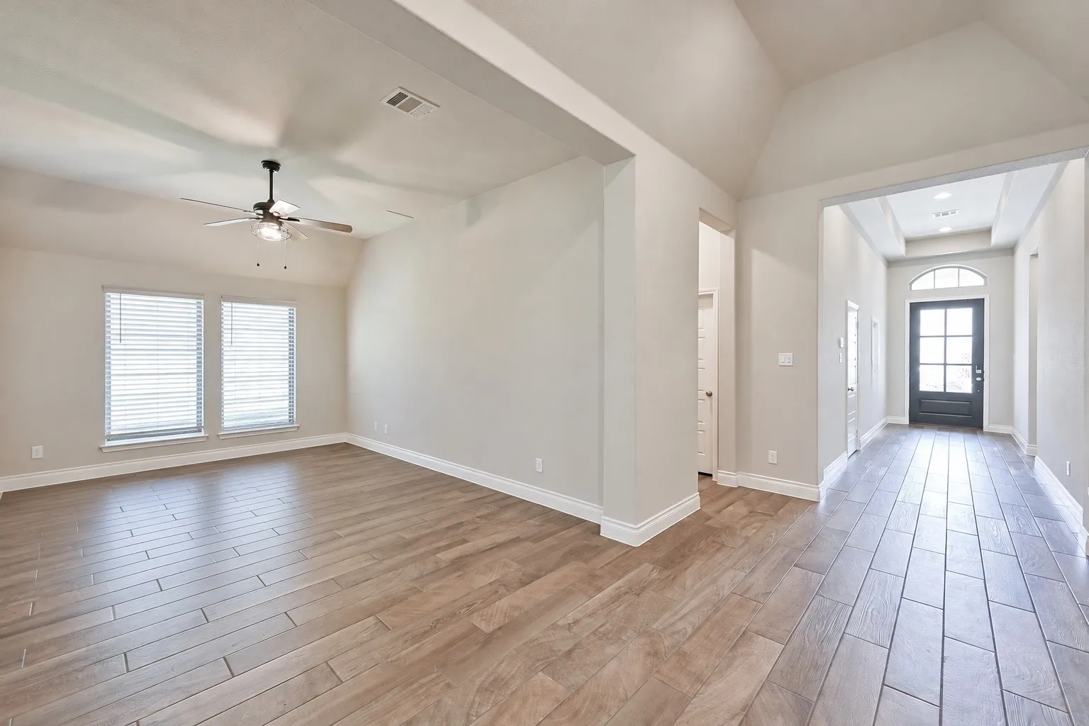 Wood-finish flooring throughout, vaulted ceiling, and recessed lighting in the entry