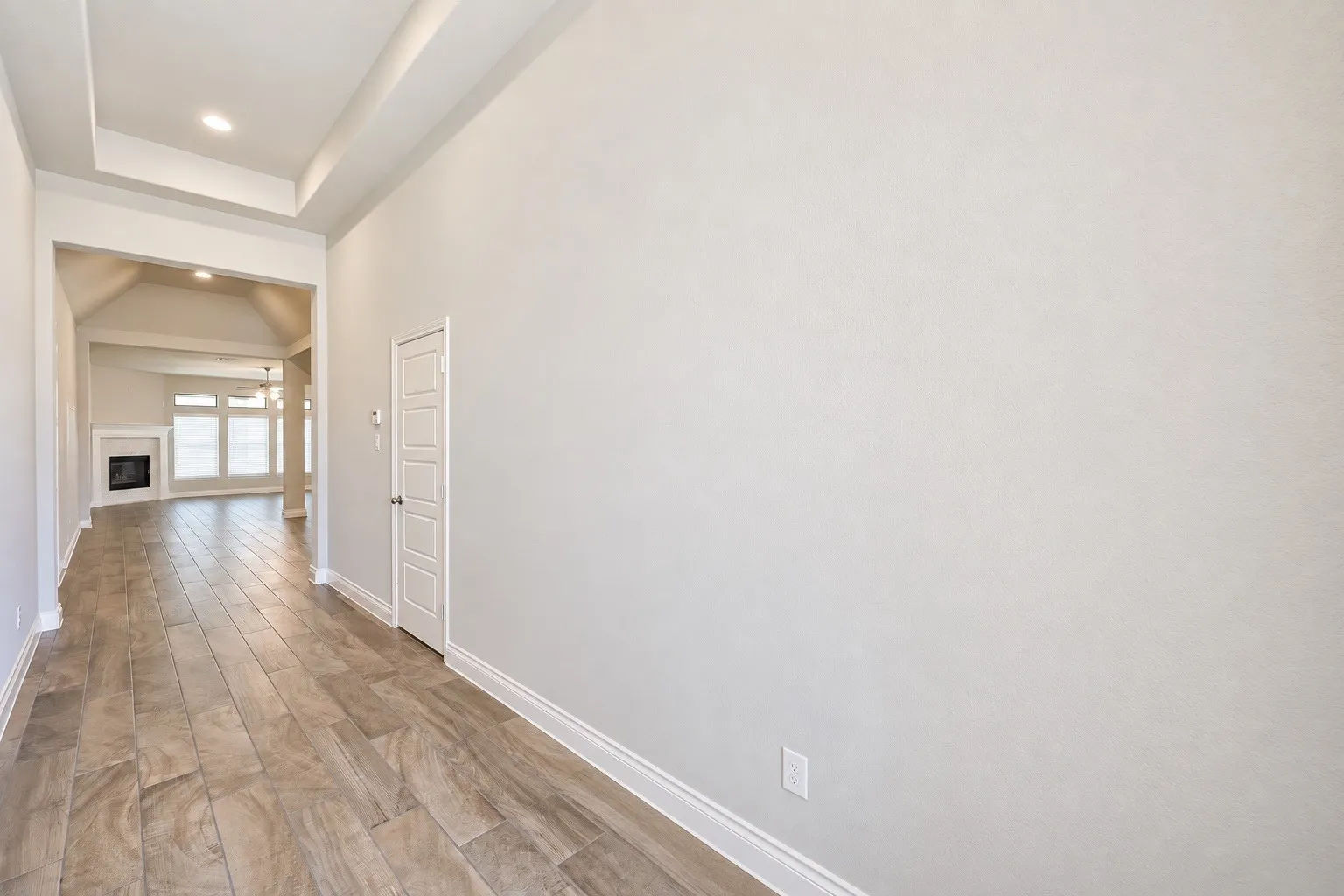 Wood-finish flooring, tray ceiling, recessed lighting, white trim, and a built-in pantry