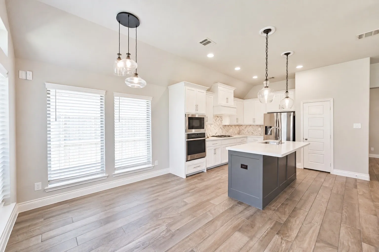 Open-concept living space featuring wood-finish flooring and a vaulted ceiling