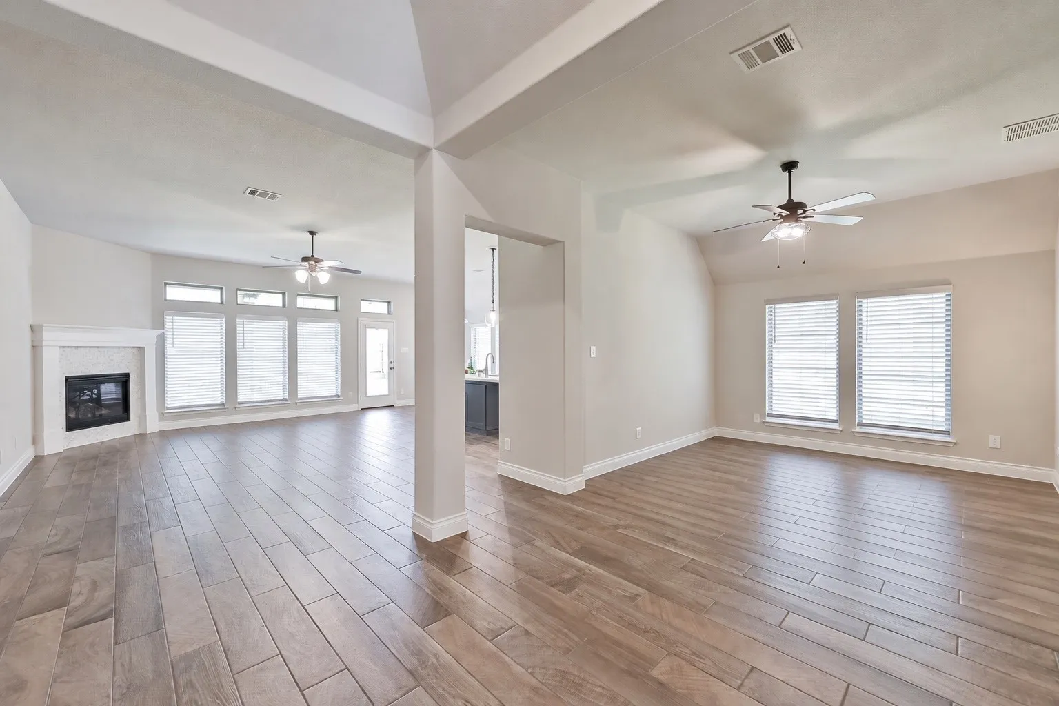 Vaulted ceilings, wood-finish flooring, and multiple windows with blinds