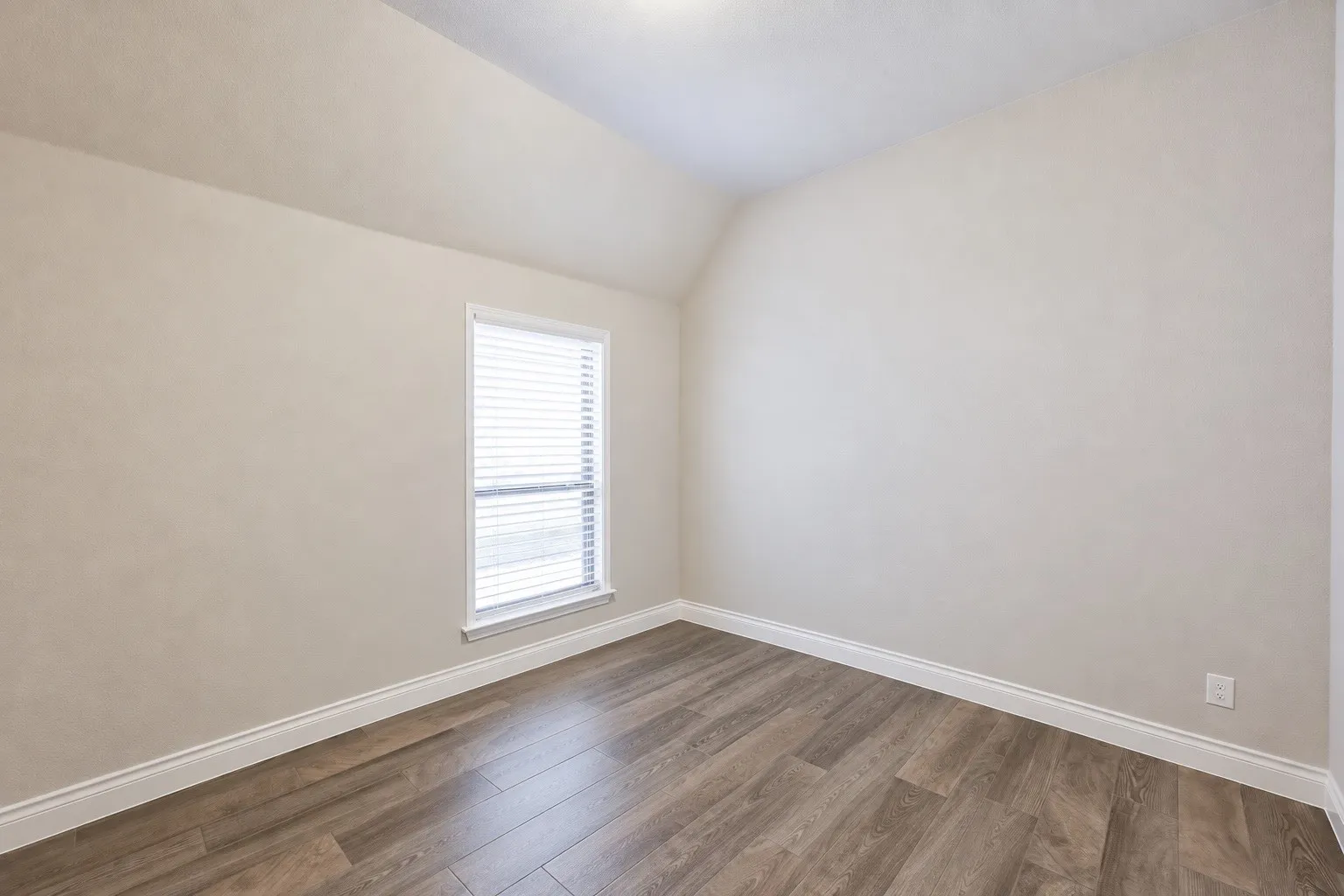 Wood-finish flooring with white trim and a recessed window