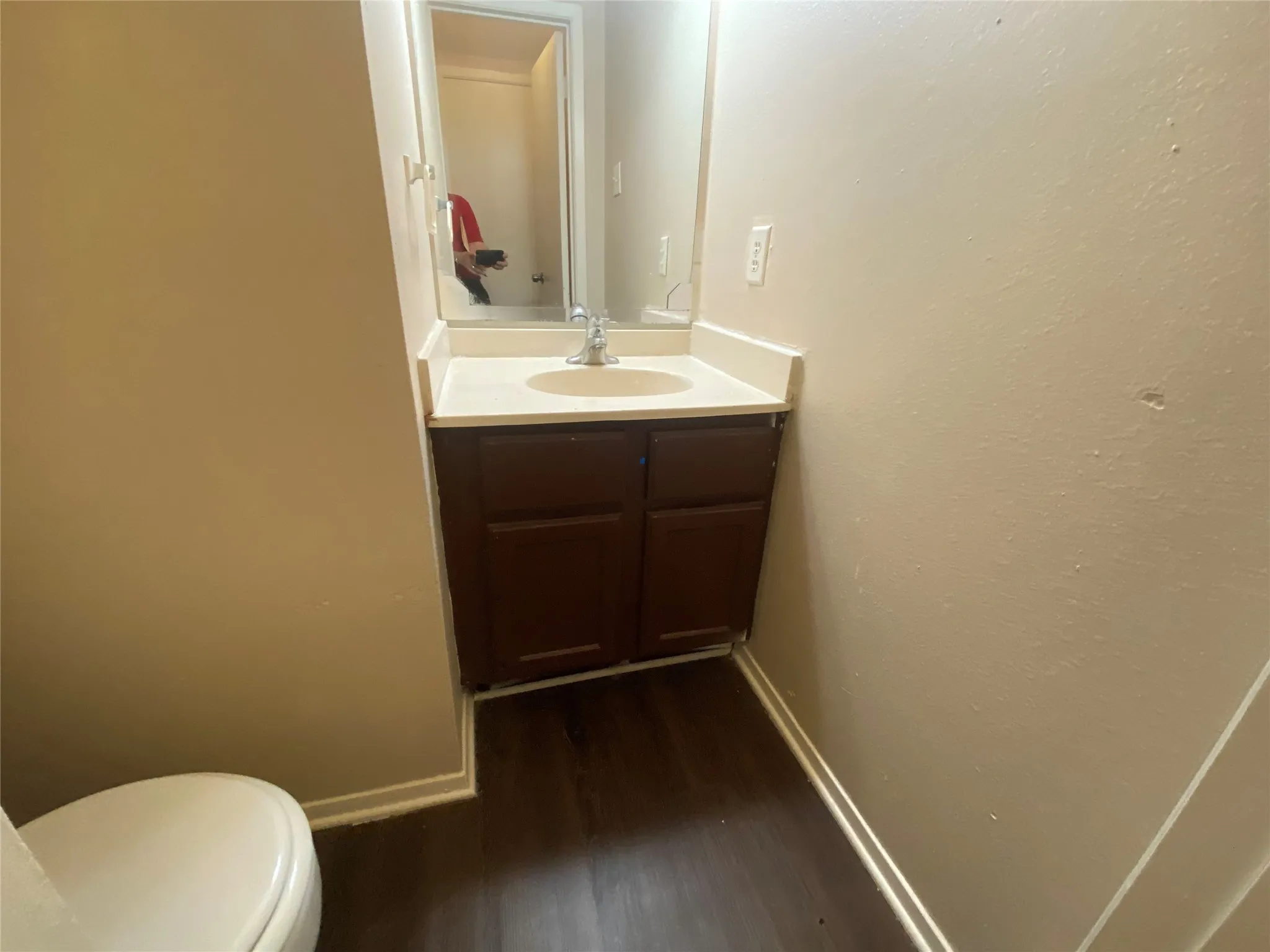 Half bath featuring baseboards, wood finished floors, toilet, and vanity