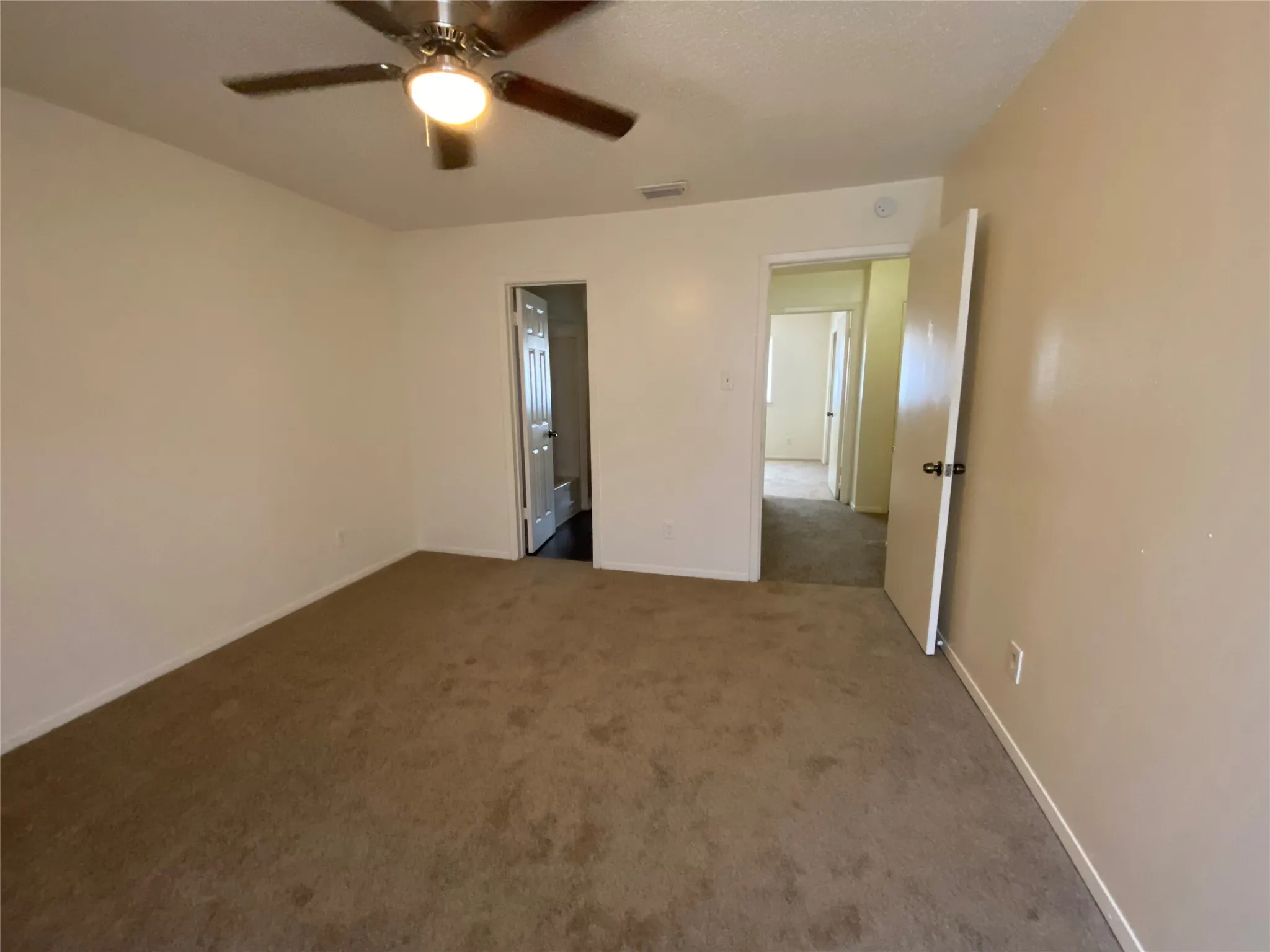 Empty room with baseboards, visible vents, ceiling fan, and carpet floors