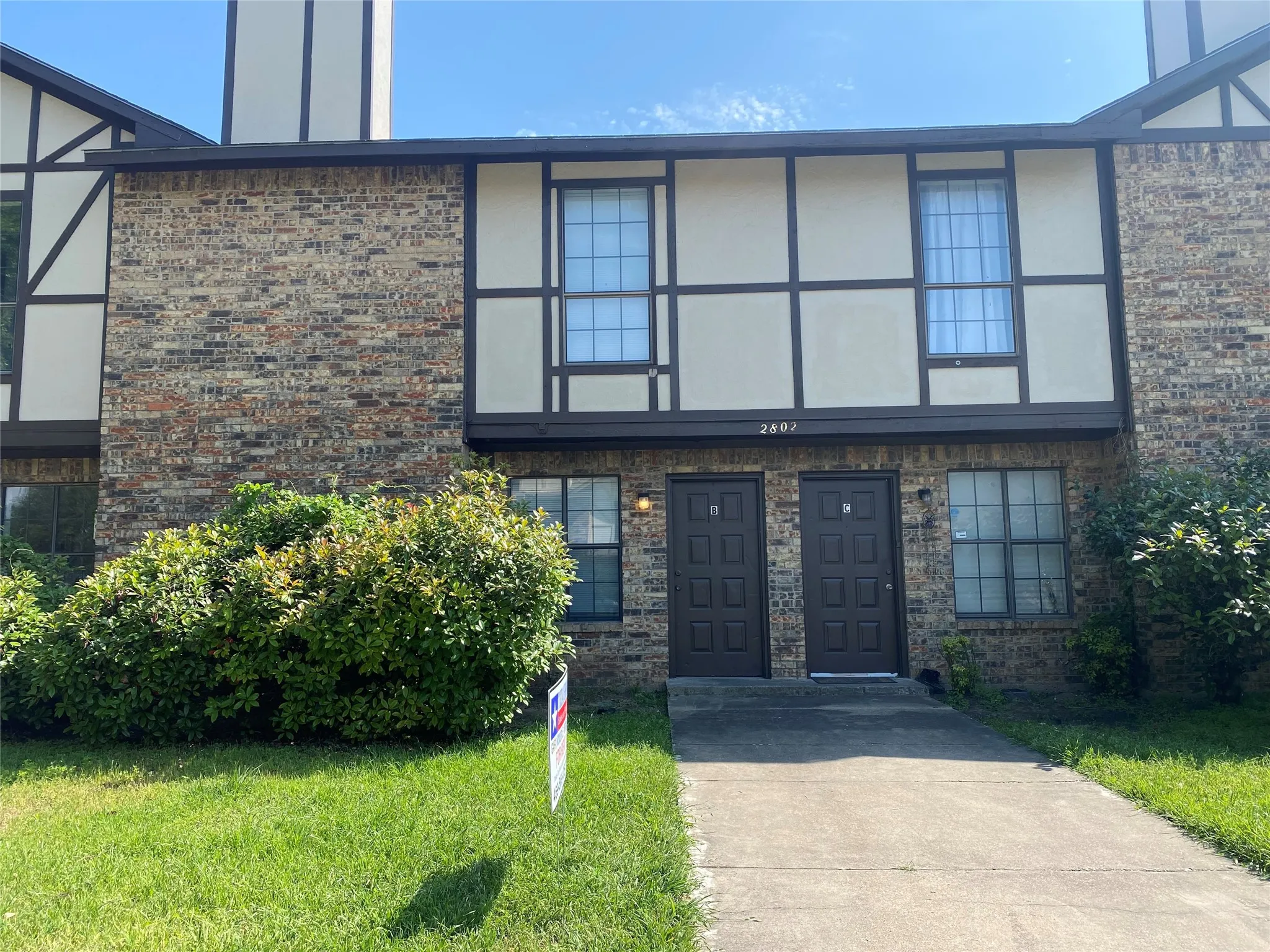 View of front of house featuring stucco siding, a front lawn, and brick siding