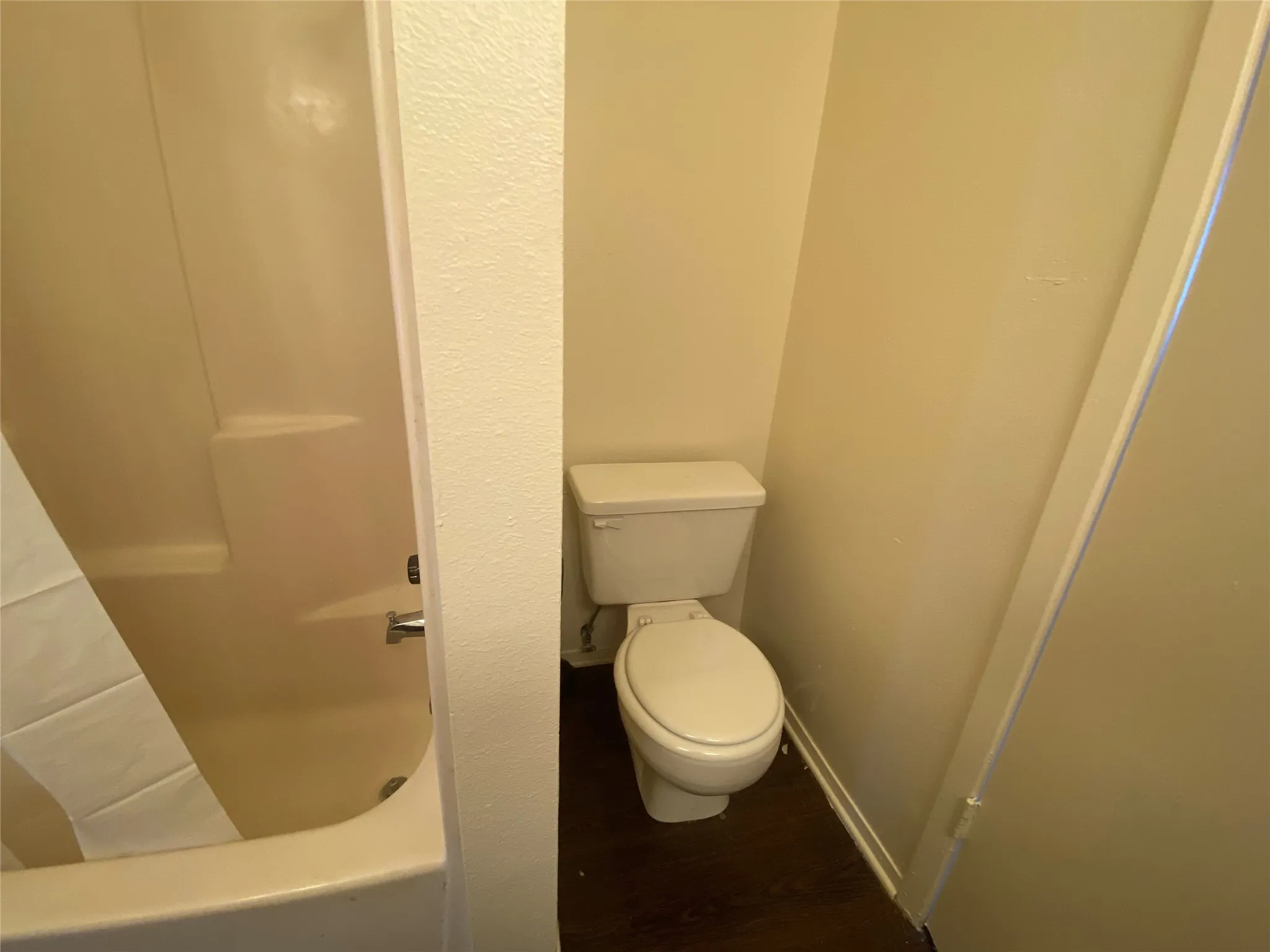 Full bathroom featuring a washtub, baseboards, walk in shower, toilet, and wood finished floors