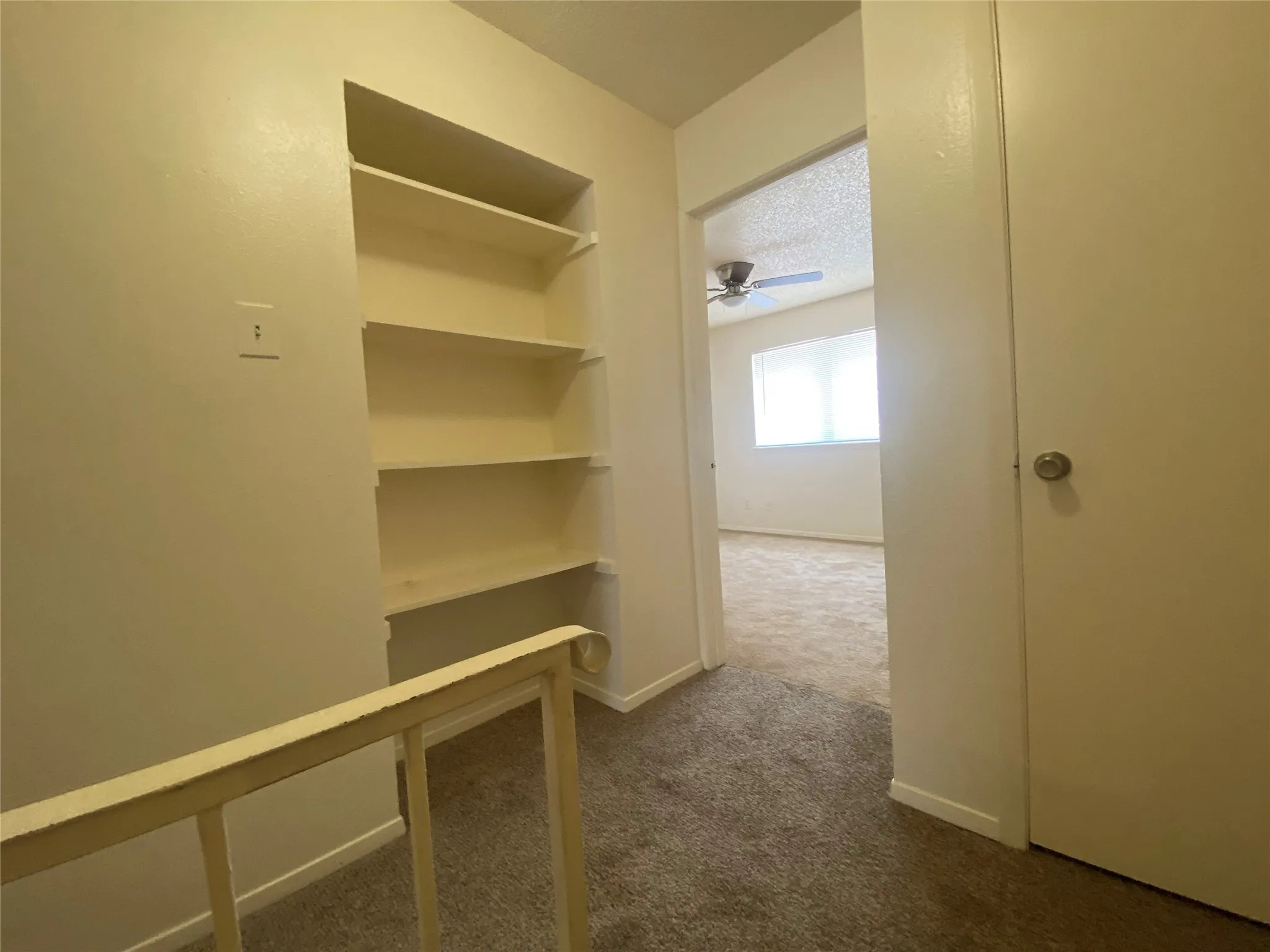 Corridor featuring dark carpet and baseboards