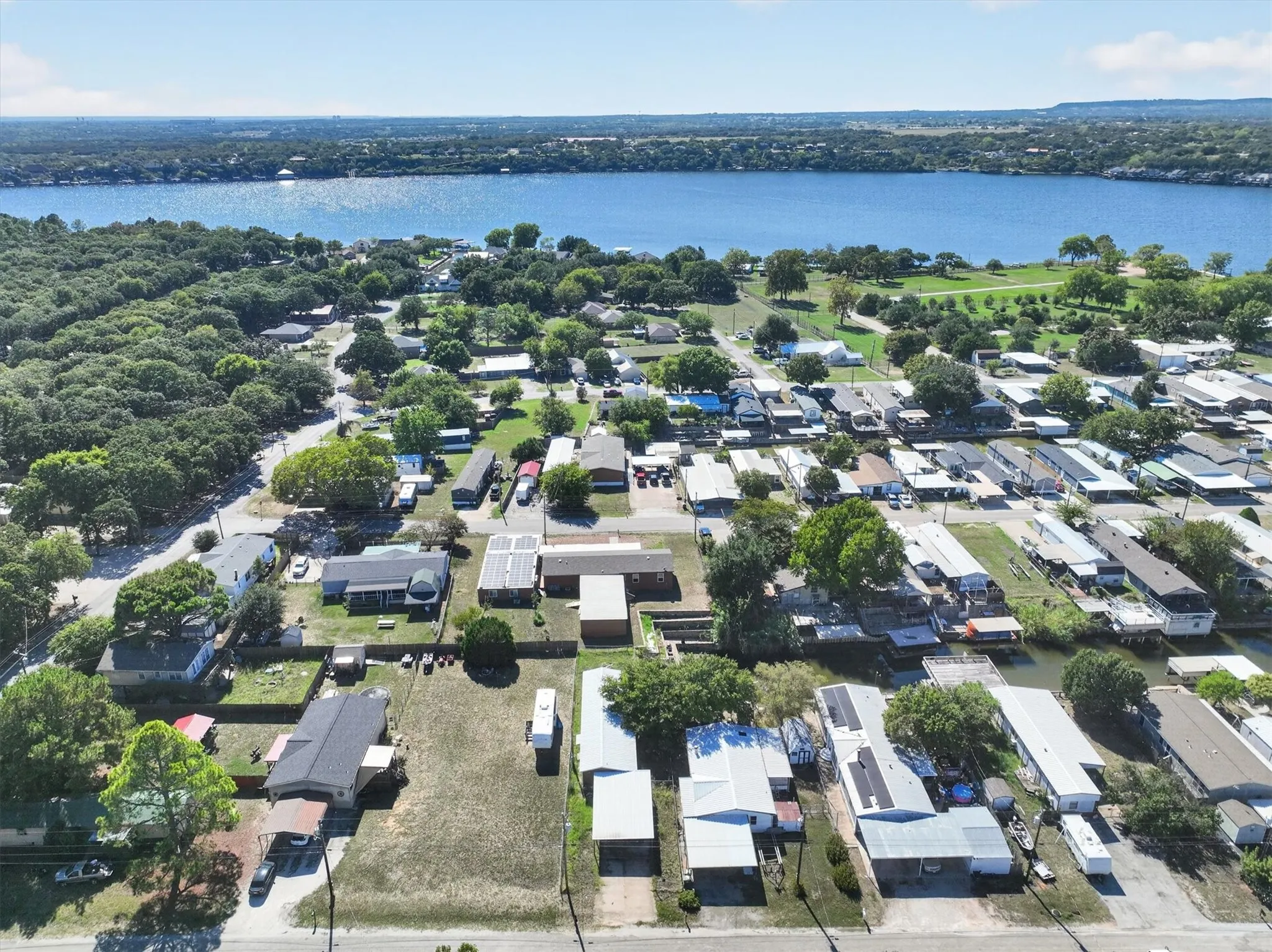 Expansive water frontage, residential properties, mature trees, and clear blue skies