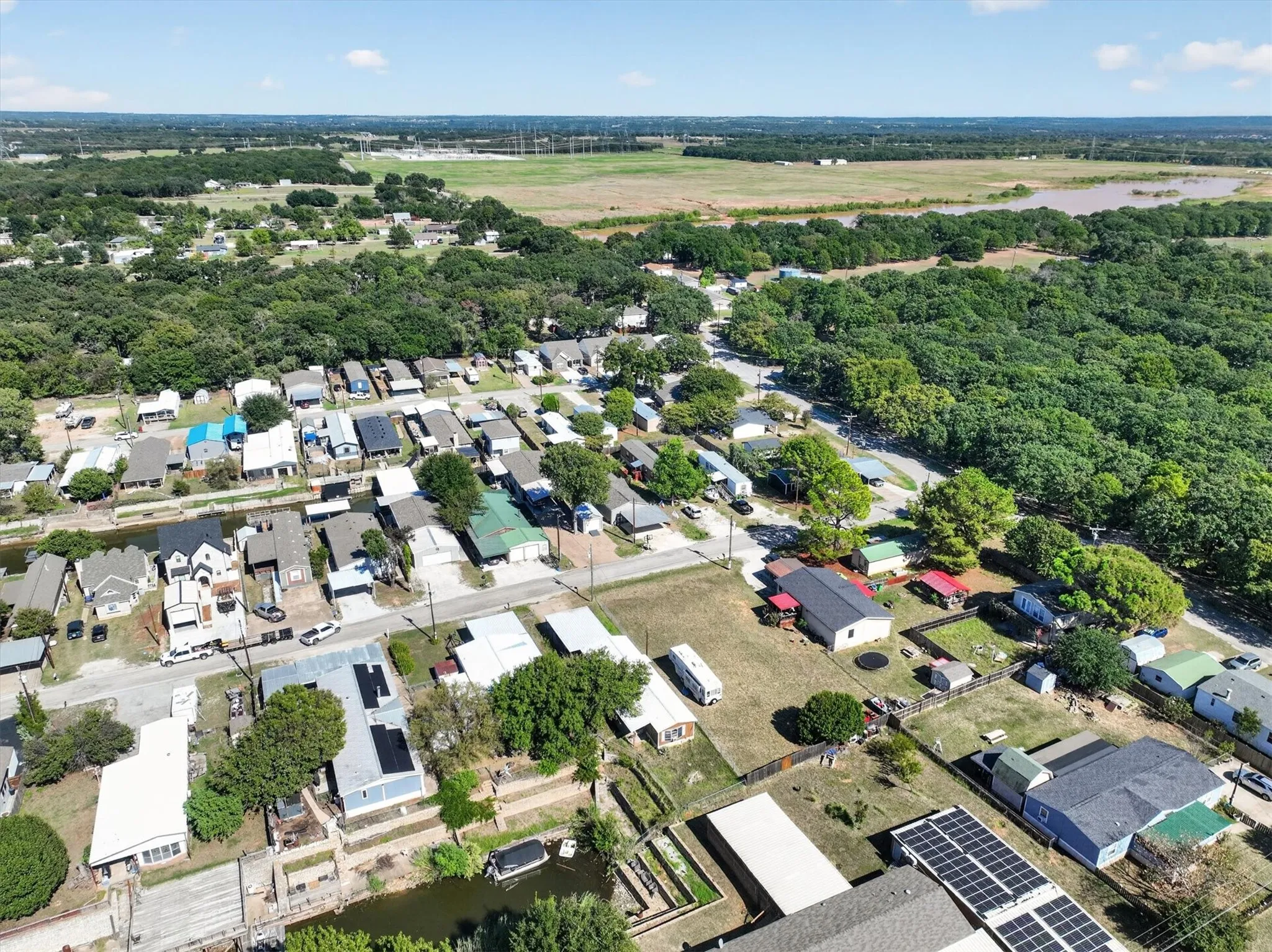 Aerial perspective showcasing a residential community with abundant mature trees and a substantial body of water