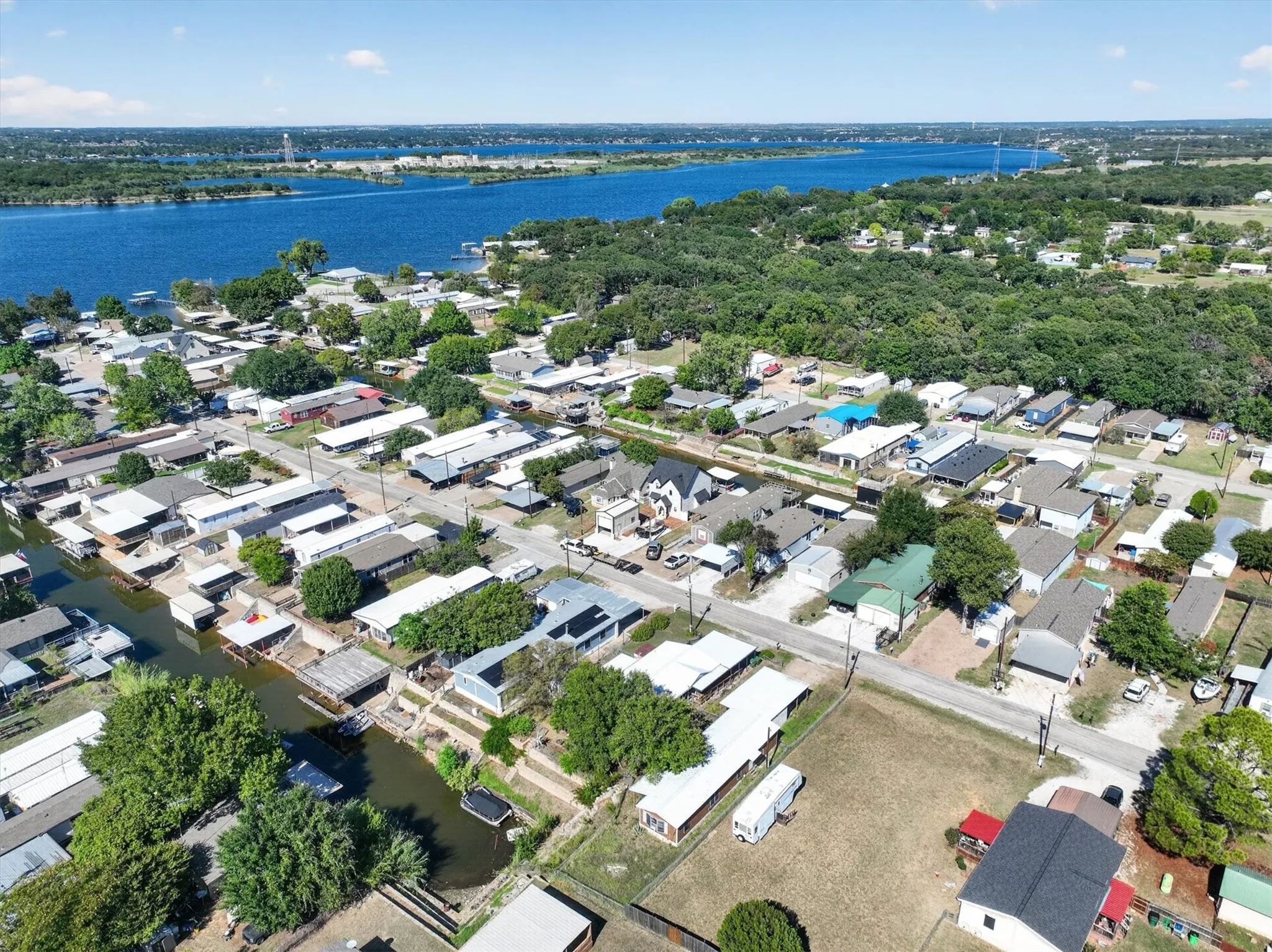 Expansive water body, residential properties, green tree canopy, boat docks, and visible roadways