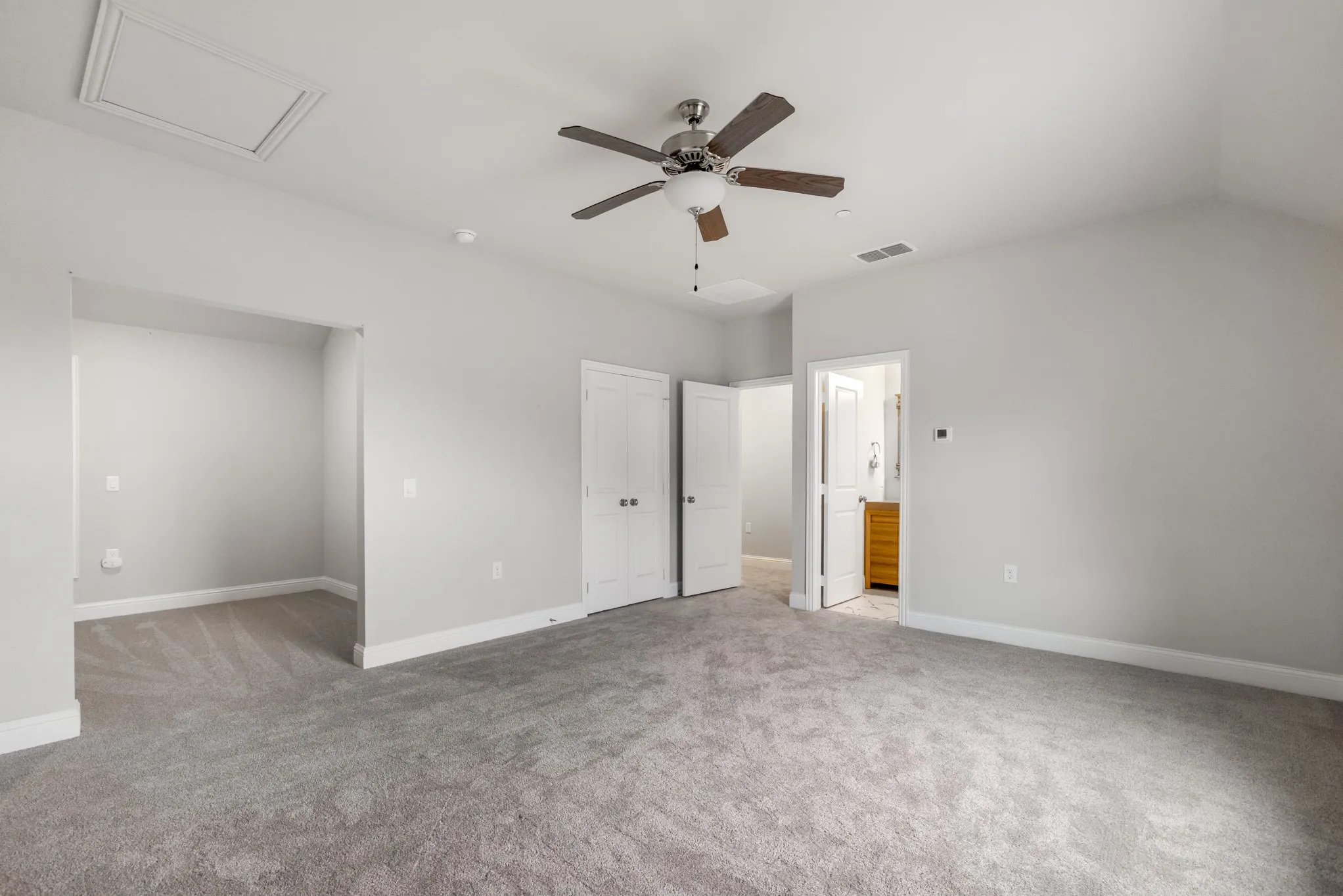 Spacious room with light gray walls, gray carpeting, and a ceiling fan