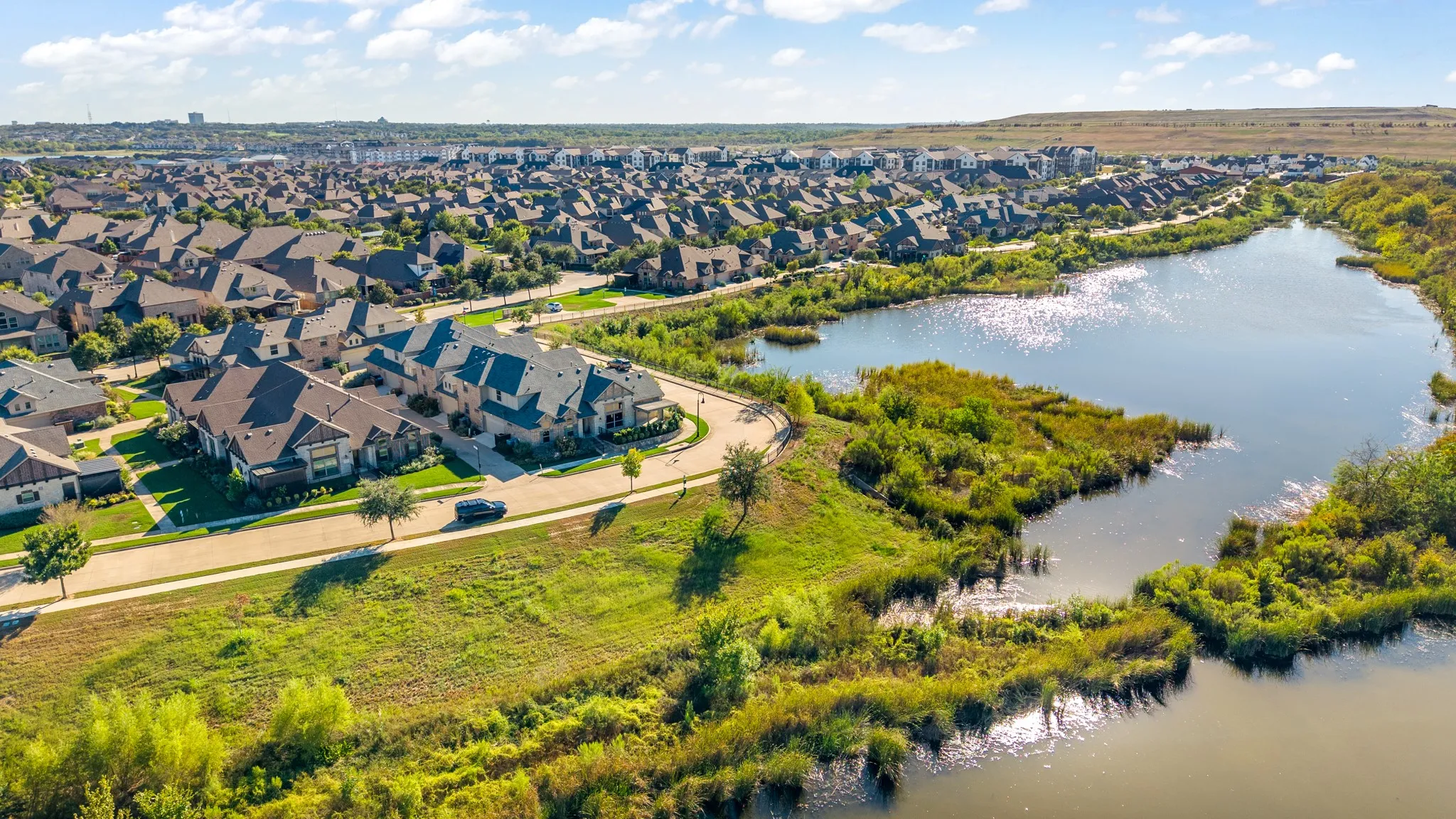 Sprawling residential community featuring tree-lined streets, manicured landscaping, and waterfront proximity