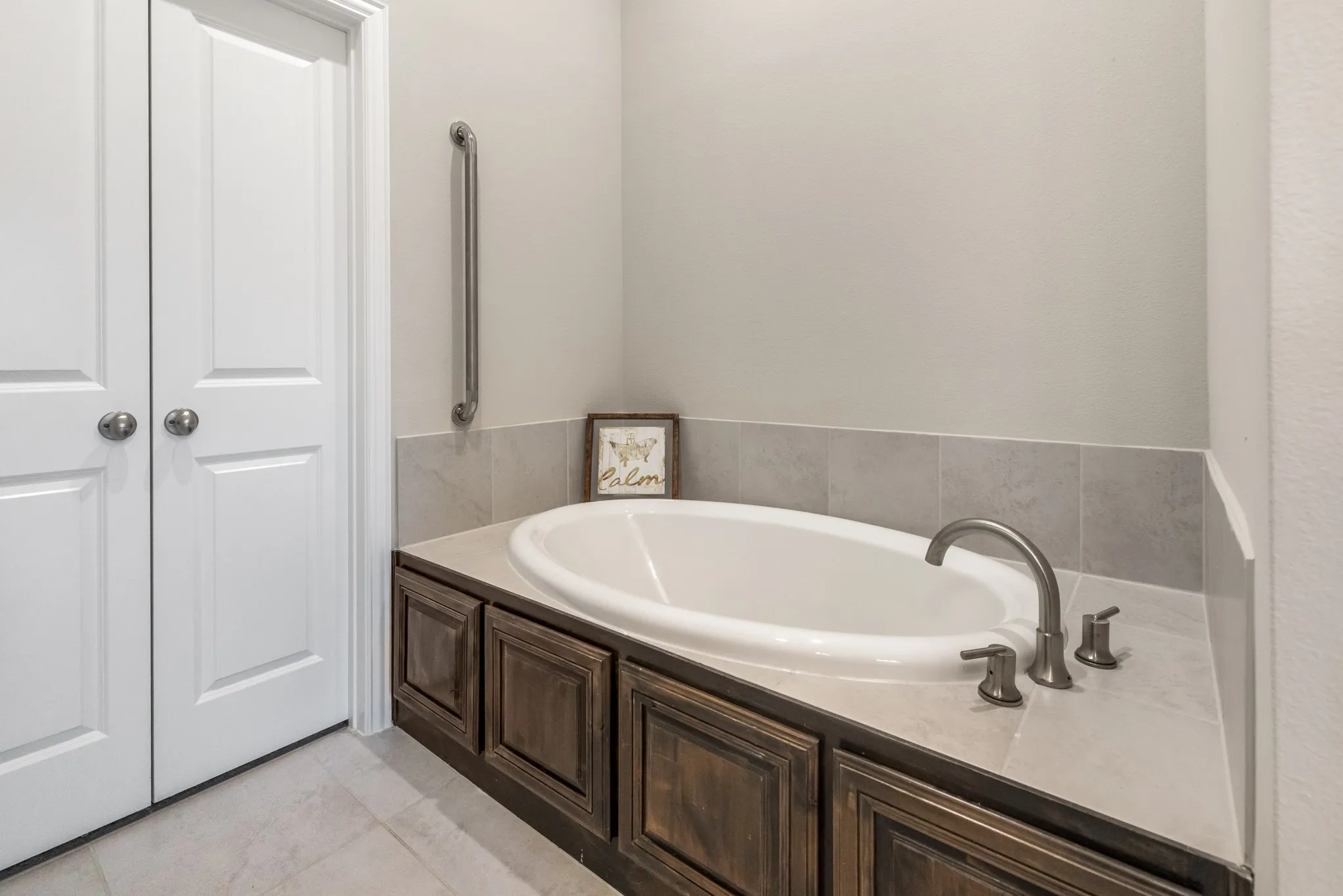 Built-in soaking tub with a deck-mounted faucet, surrounded by wood-finish cabinetry, and a tile backsplash