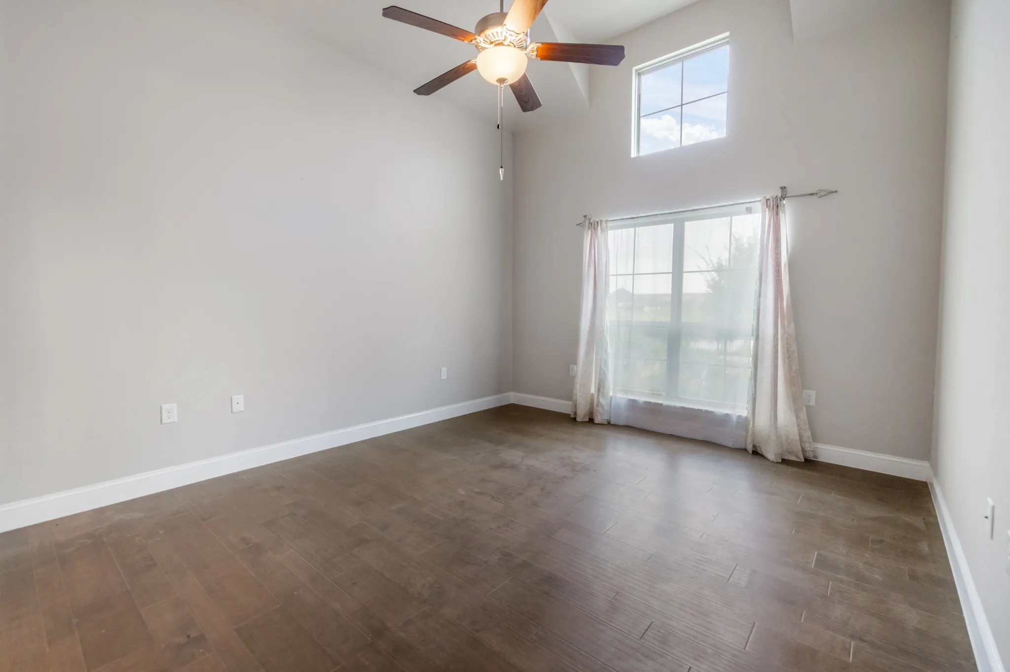 Vaulted ceiling with a ceiling fan, wood-finish flooring, and multiple windows