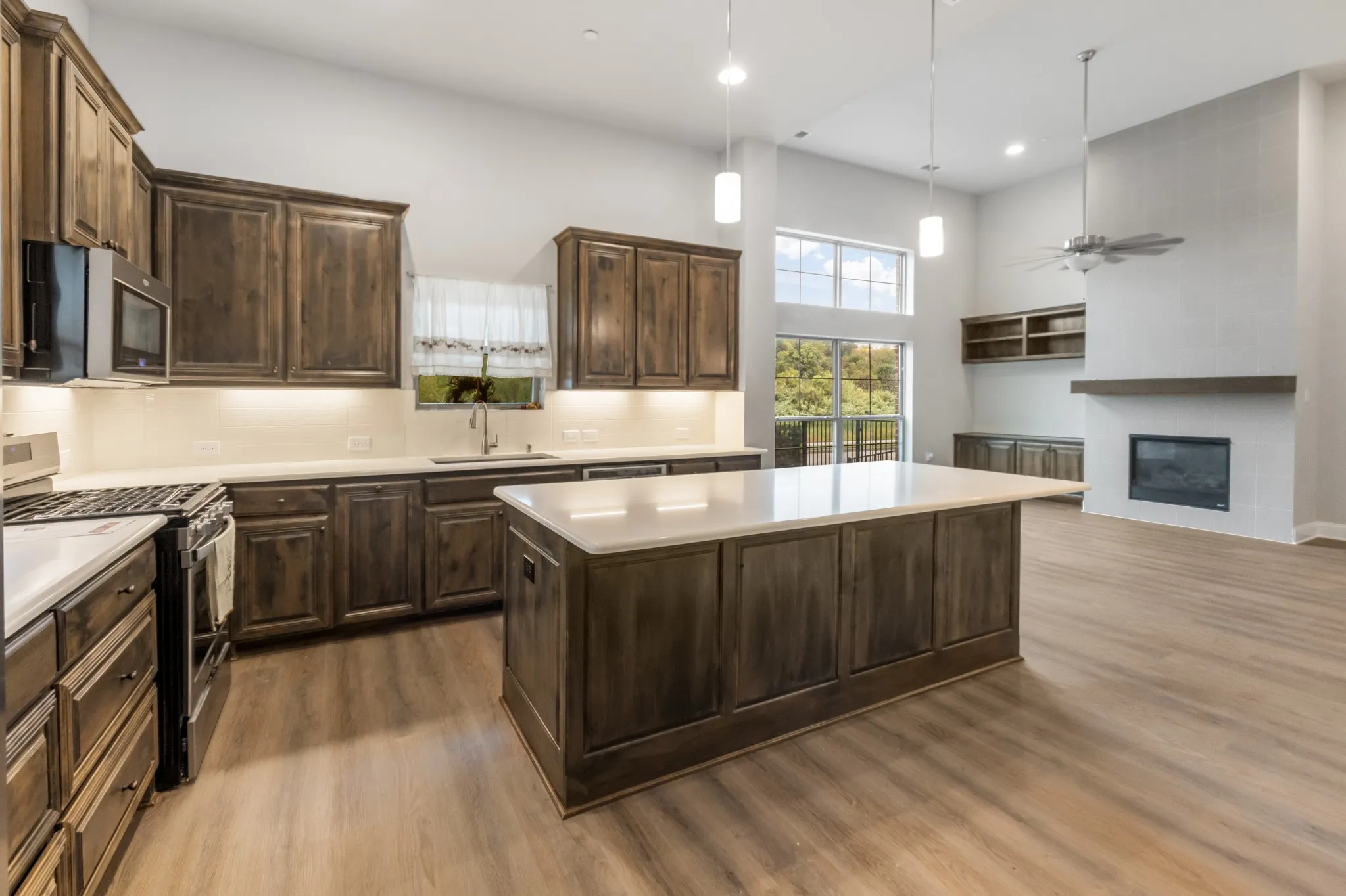 Kitchen island with solid surface countertop, wood-finish cabinetry, stainless steel appliances, and wood-finish flooring