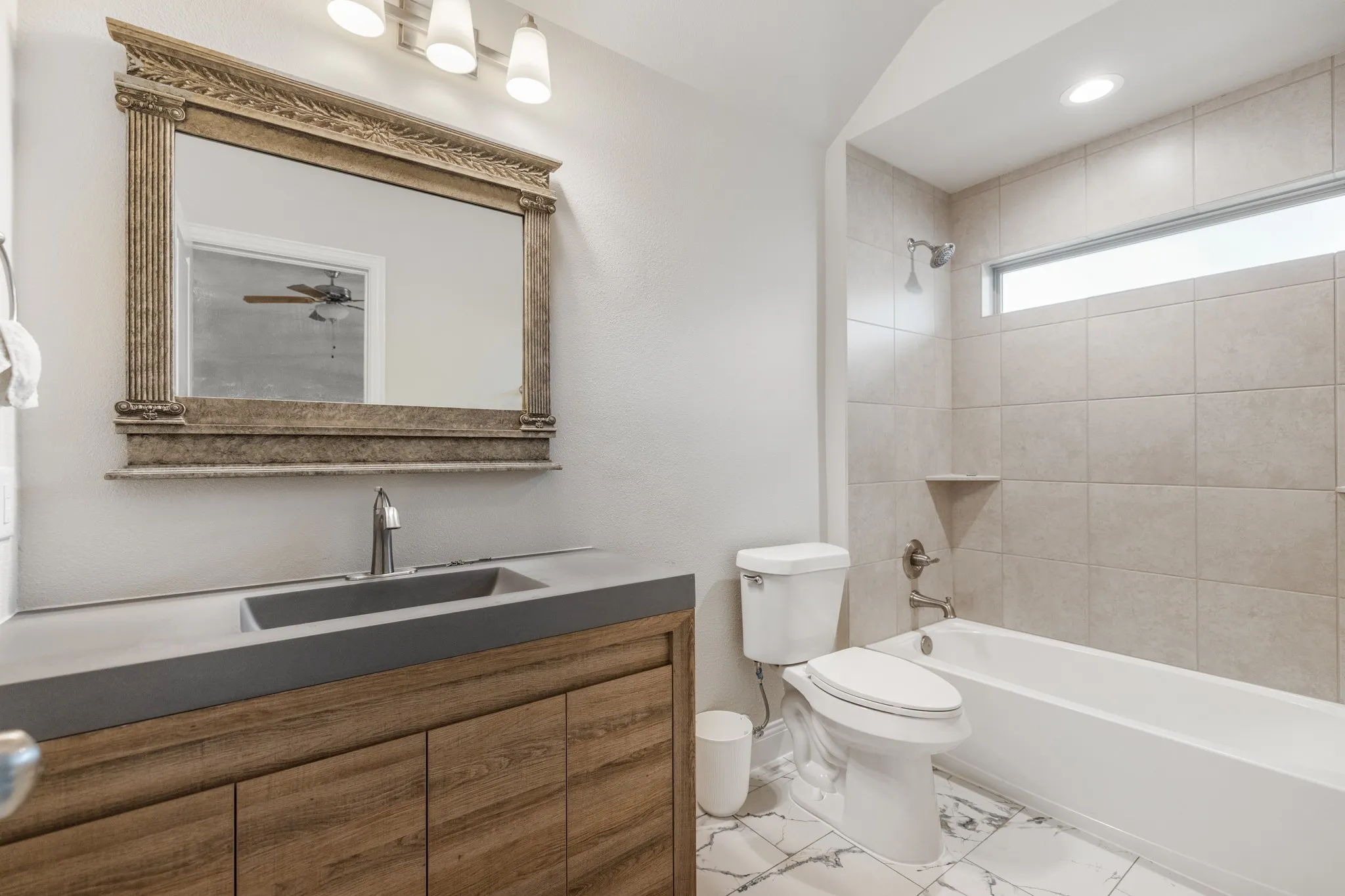Wood-finish vanity with an integrated rectangular sink and a decorative framed mirror