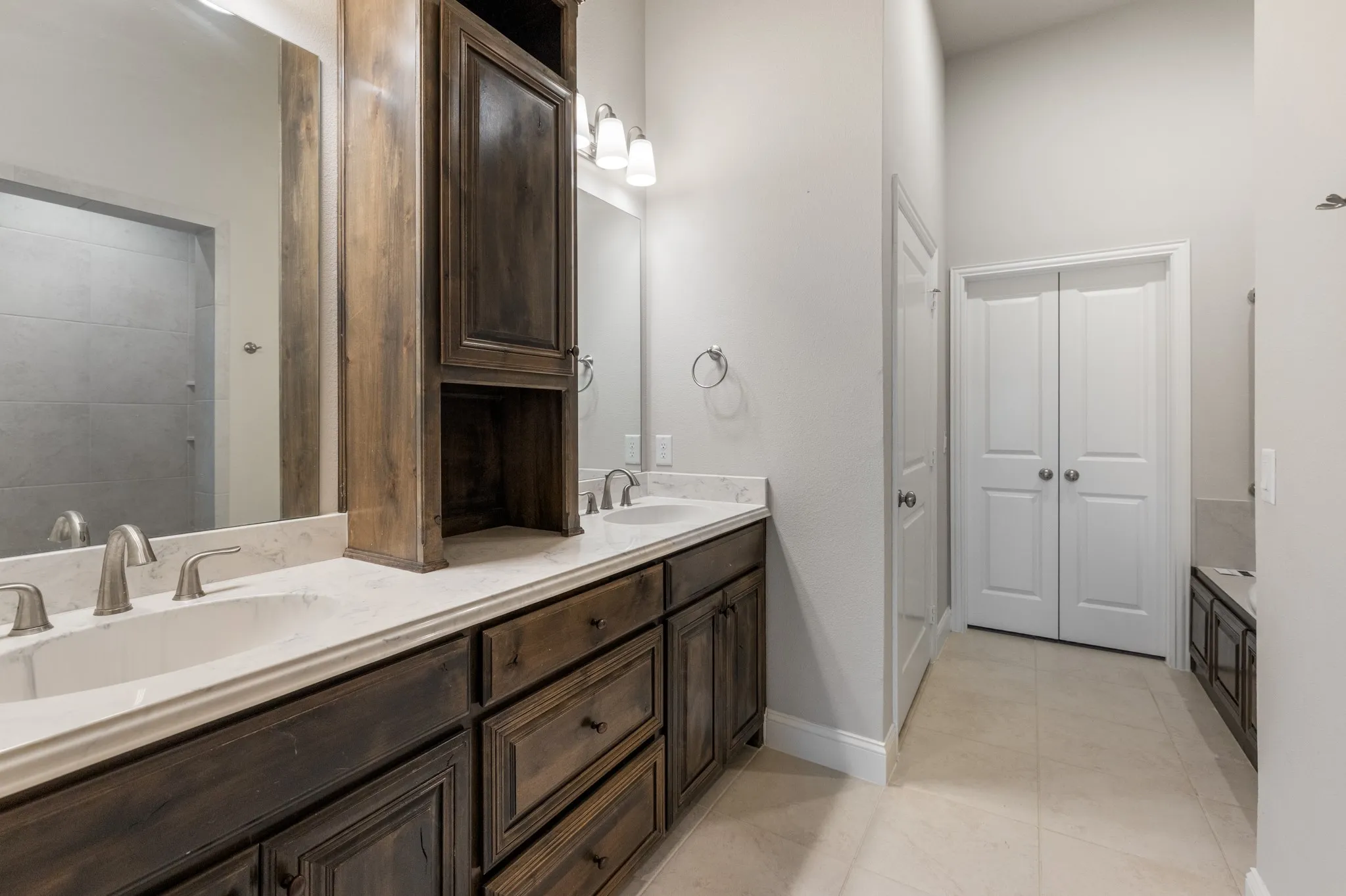 Dual sinks set in a stone-finish countertop, flanked by dark wood-finish cabinetry
