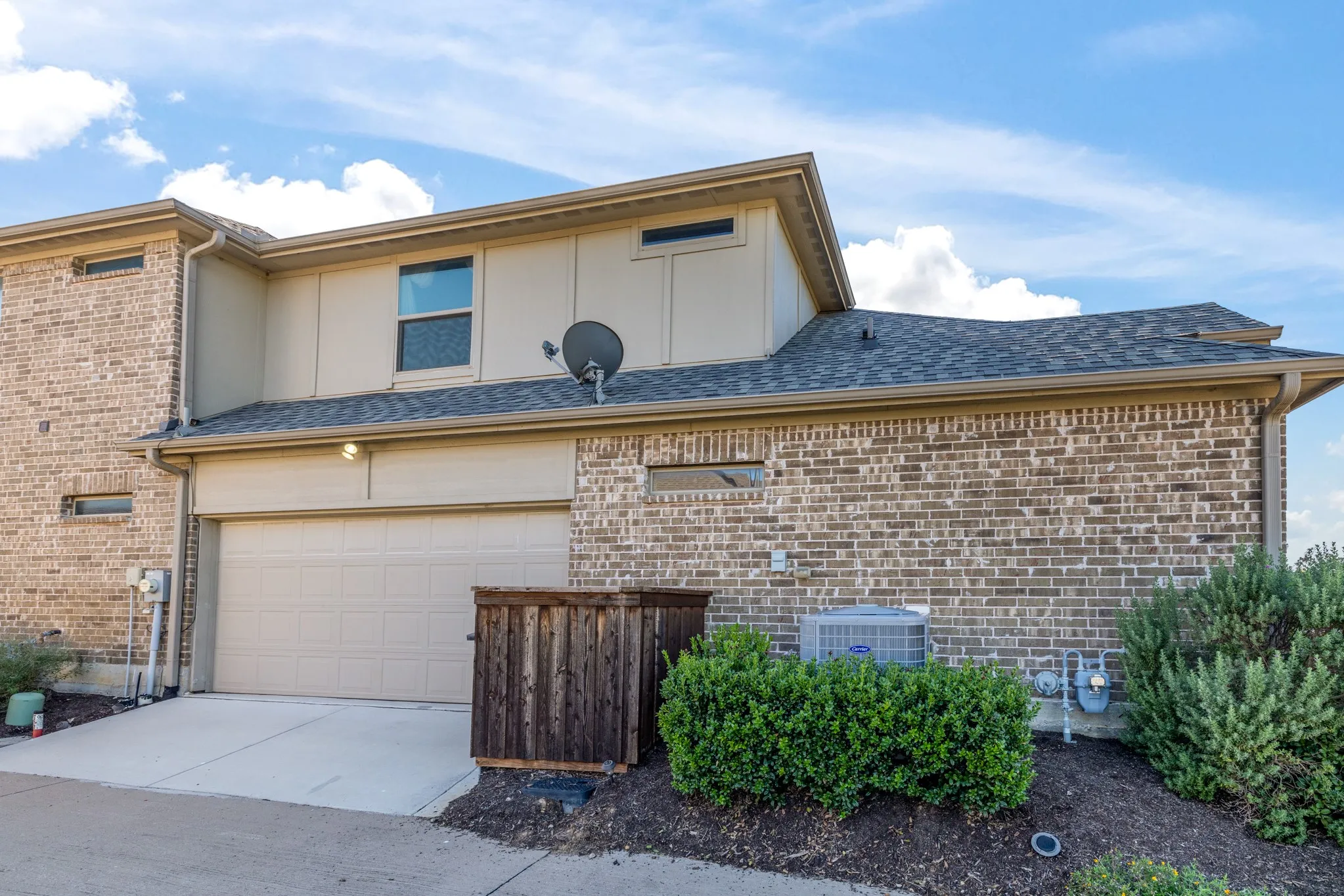 Brick exterior with a multi-level design, attached garage, and a sloped shingle roof