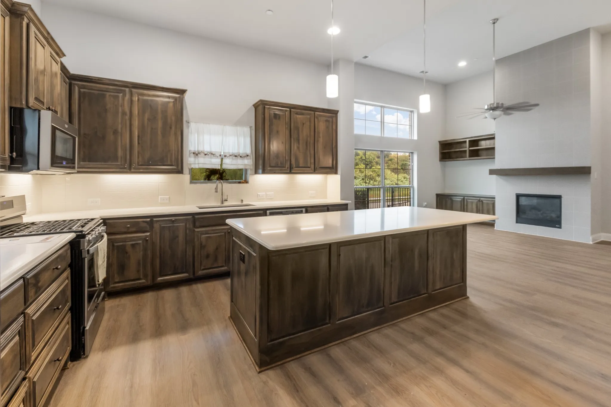 Open-concept living area featuring a kitchen with wood-finish cabinetry, a large kitchen island, and stainless steel appliances