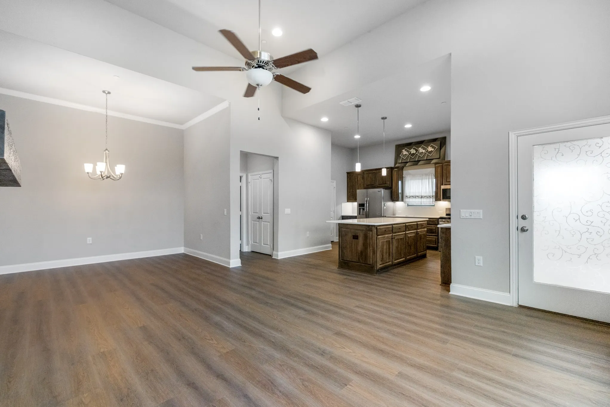 Vaulted ceilings with a ceiling fan, wood-finish flooring, and a chandelier