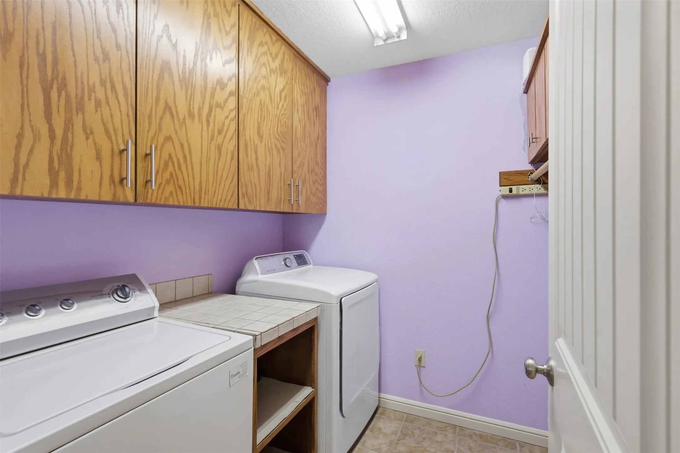 Built-in wood cabinetry with chrome hardware, tile countertop, and vinyl flooring