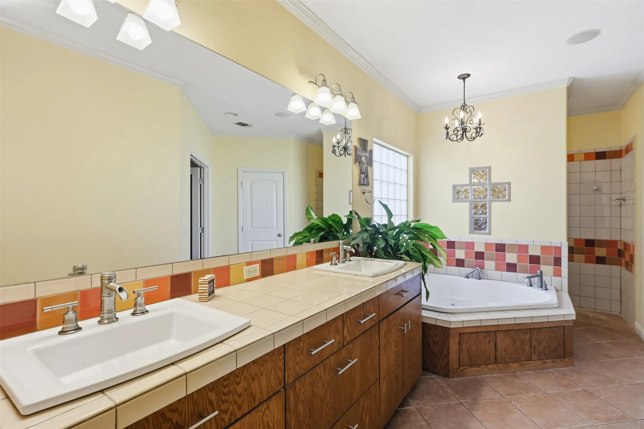 Dual vanity with wood-finish cabinetry, tile countertop, and rectangular undermount sinks