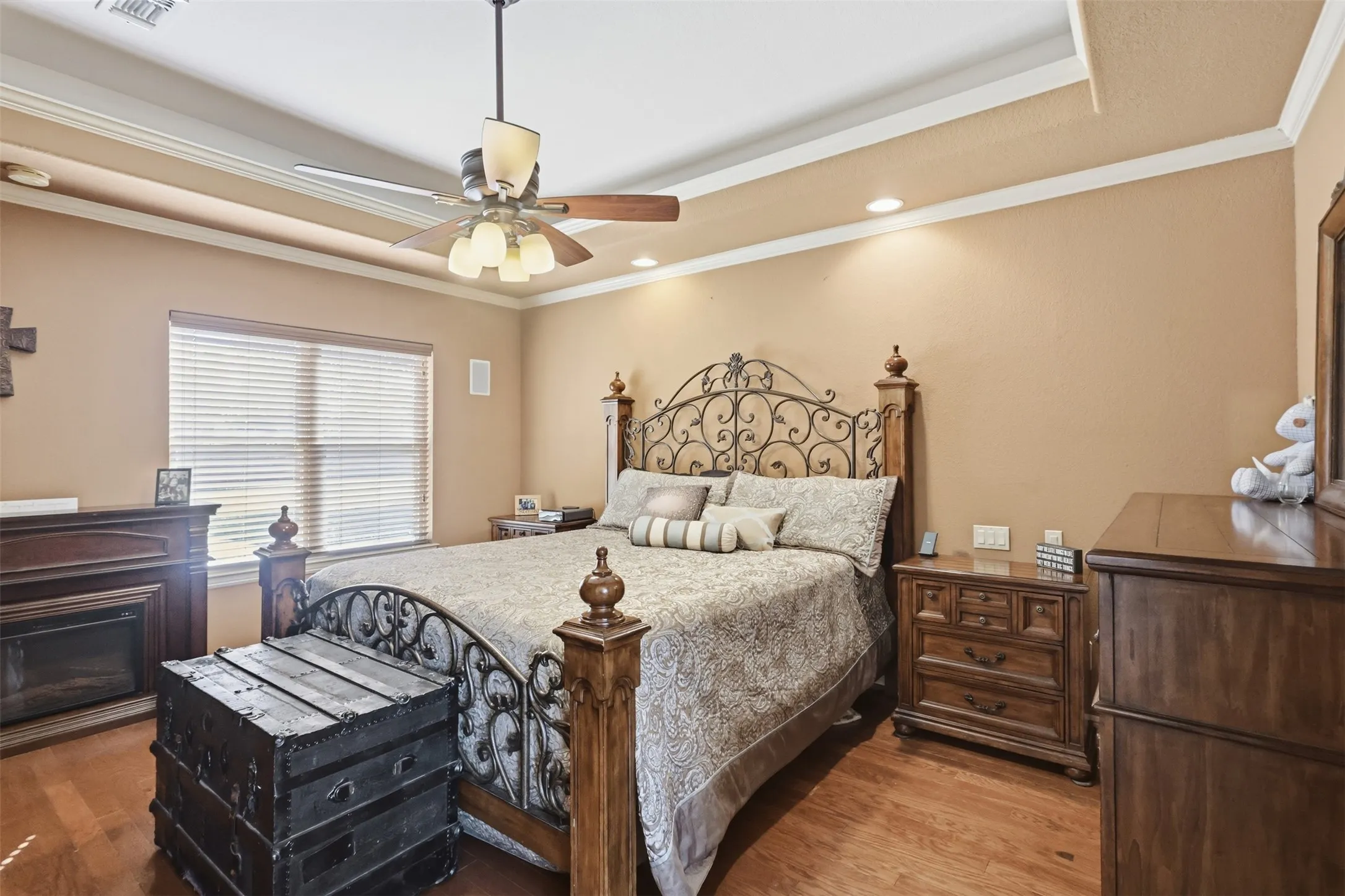 Wood-finish flooring, tray ceiling, recessed lighting, ceiling fan, and a built-in fireplace with wood mantel