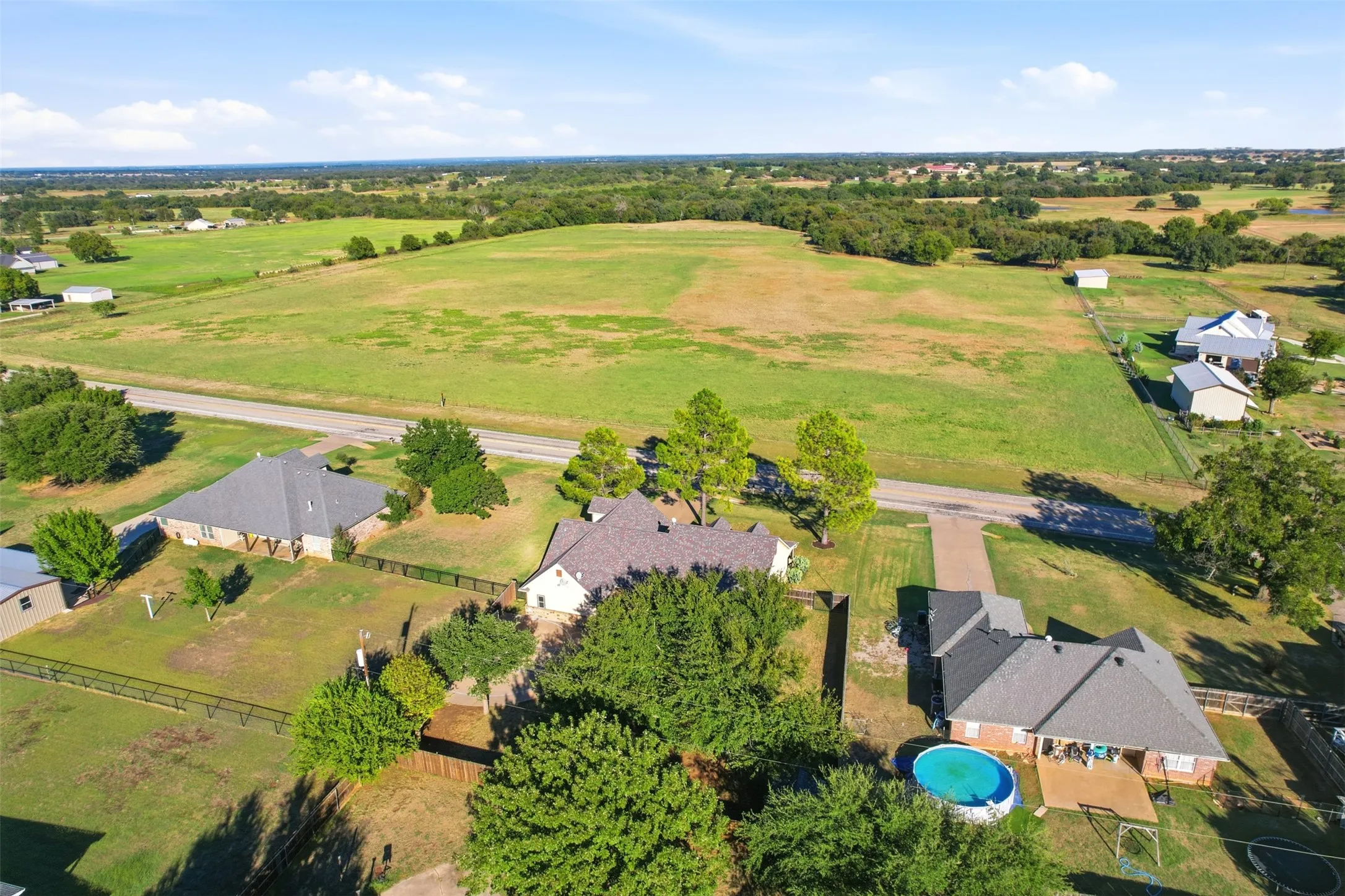 Expansive property featuring a large green field, multiple residential structures, and mature trees