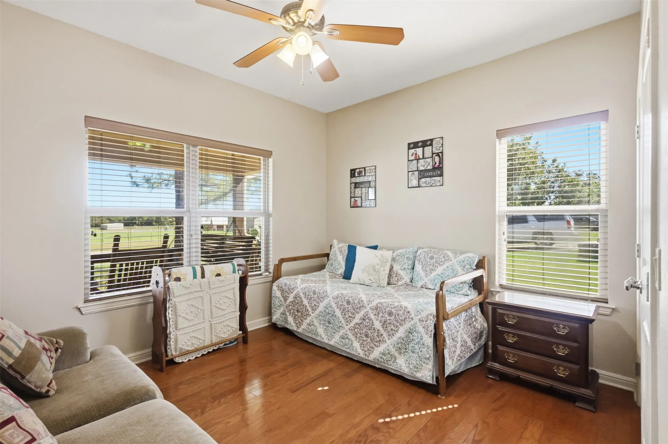 Vaulted ceiling with a ceiling fan, wood-finish flooring, and multiple windows with blinds