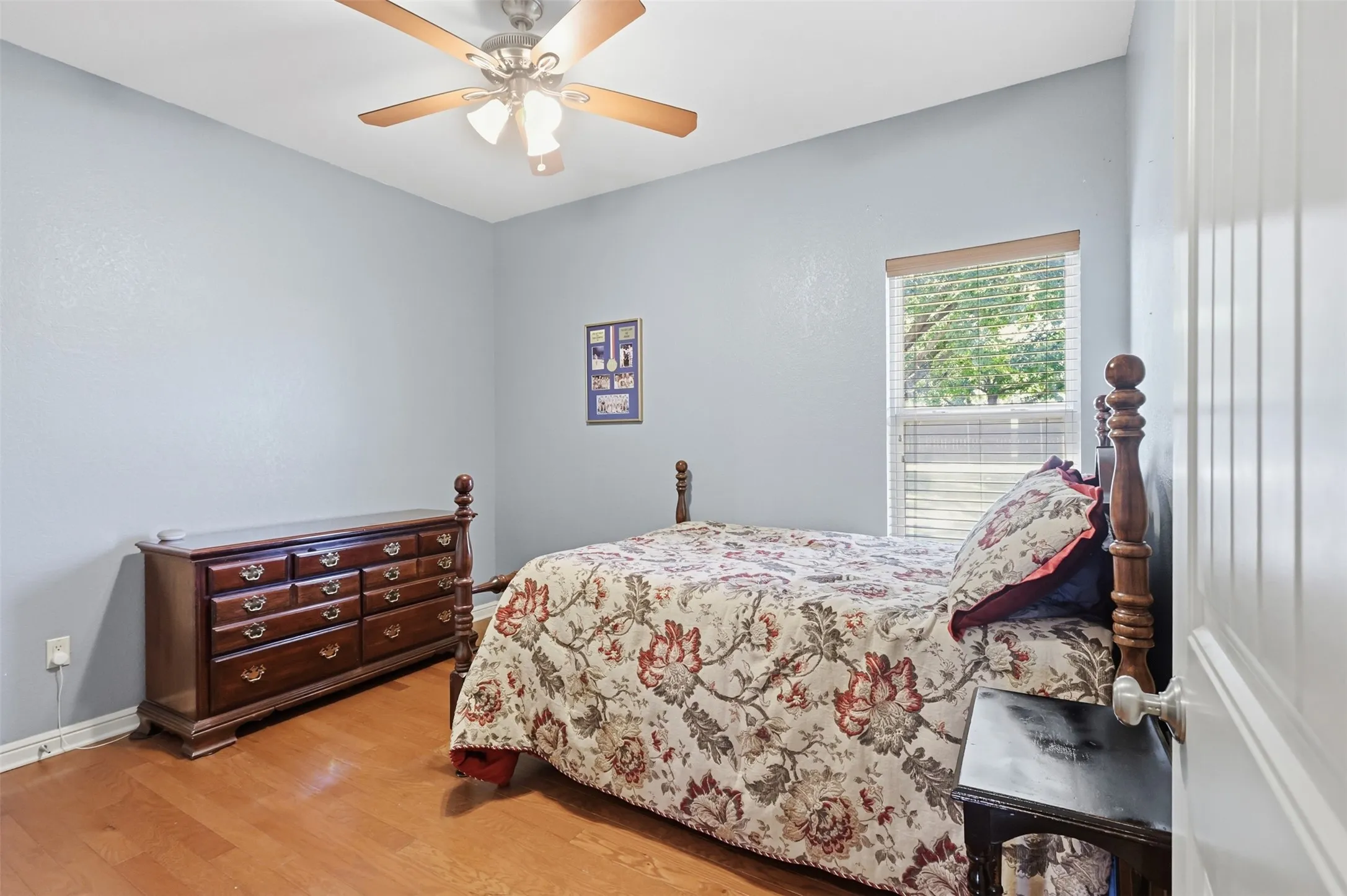 Wood-finish flooring with a ceiling fan and overhead lighting