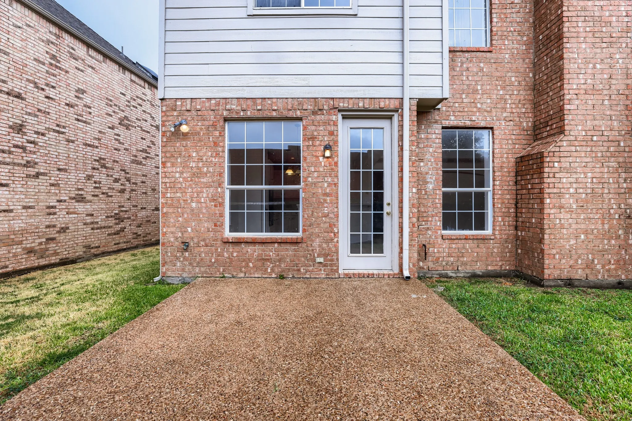 Textured aggregate patio with brick exterior and white siding