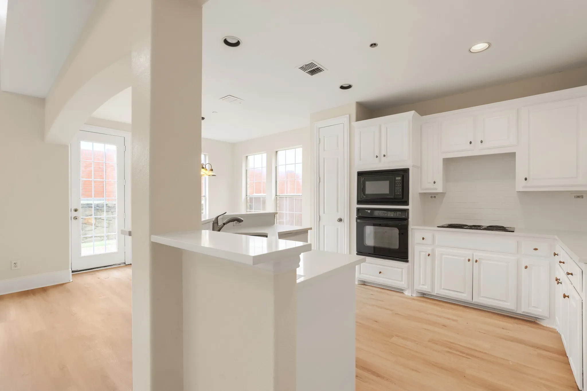 Kitchen featuring white cabinetry, built-in double ovens, a built-in microwave, white countertops, and wood-finish flooring