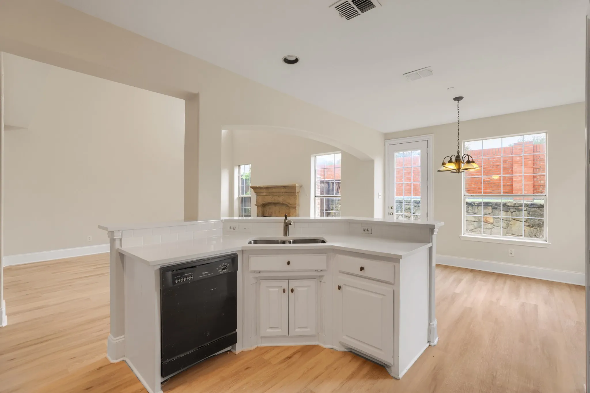 Kitchen island featuring a dual-basin sink, white cabinetry, and a built-in dishwasher