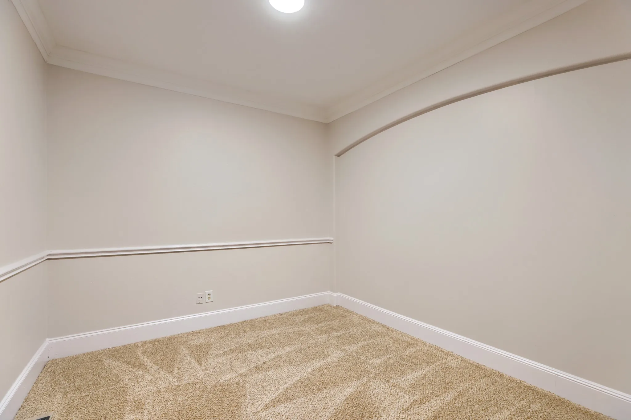 Neutral wall paint, crown molding, chair rail, and recessed wall arch