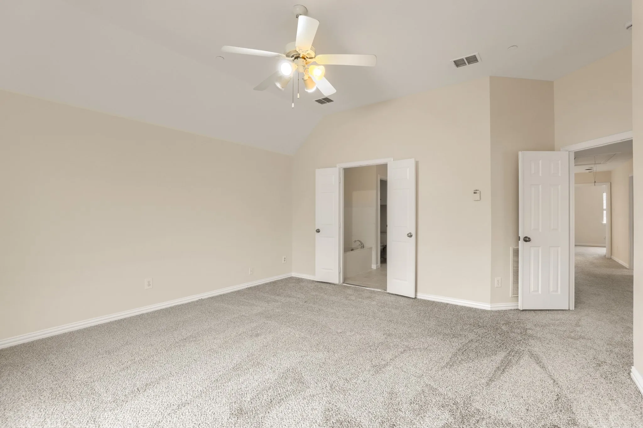 Vaulted ceiling with an attached ceiling fan, neutral carpet flooring, and white interior doors