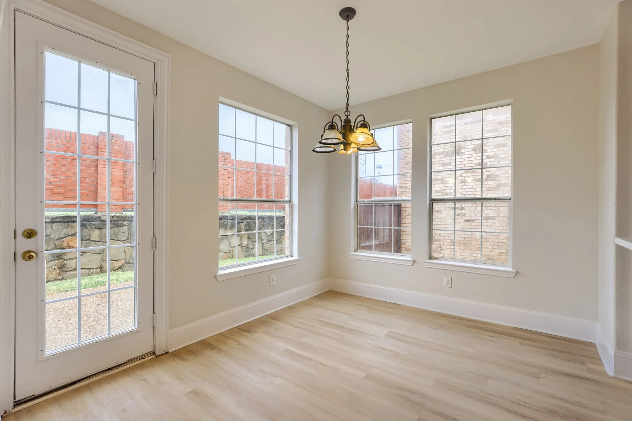 Light-toned wood-finish flooring, multiple grid-pane windows, and a glass-pane door