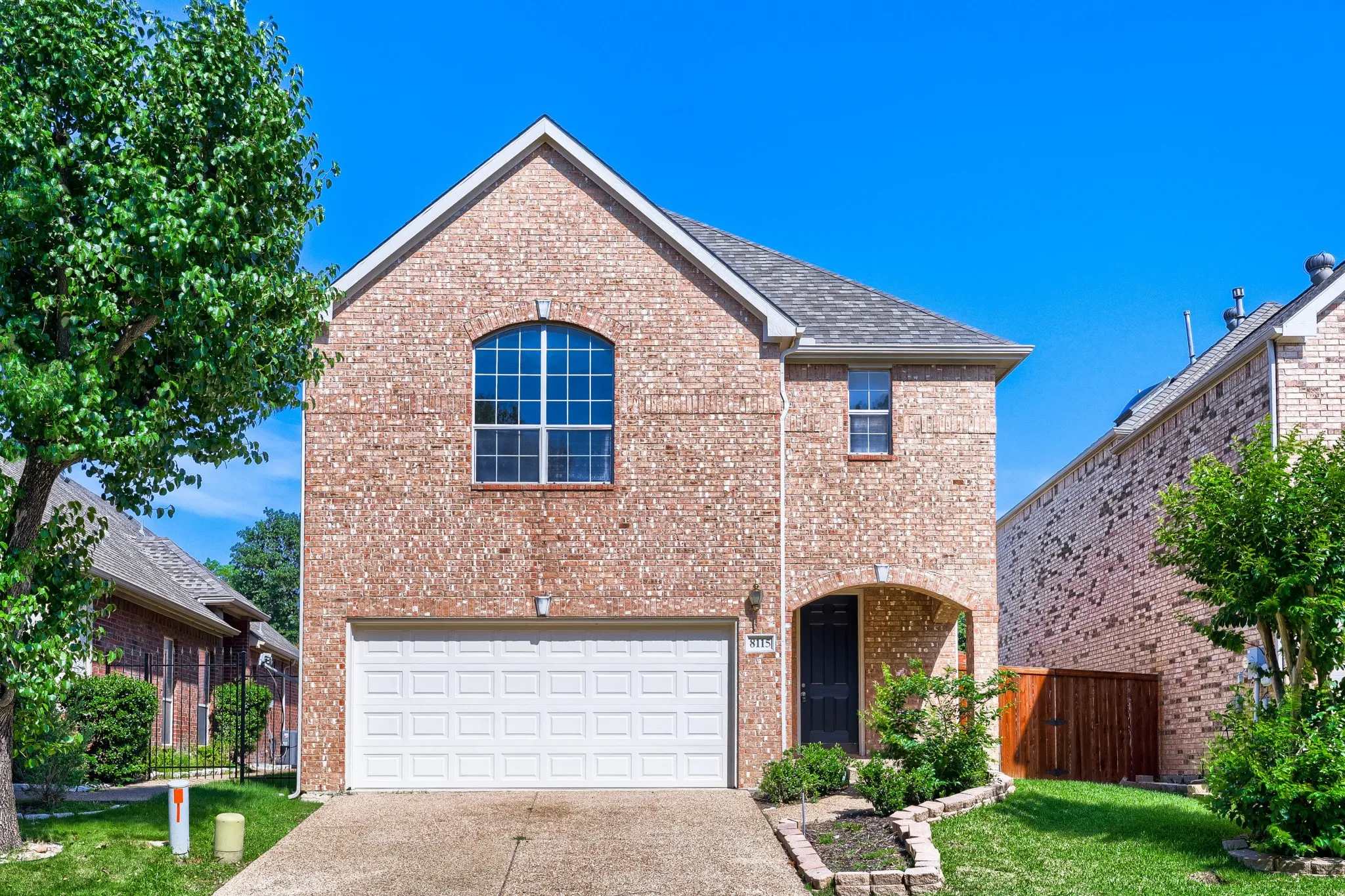 Brick exterior with an arched entry, two-car garage, and an arched window