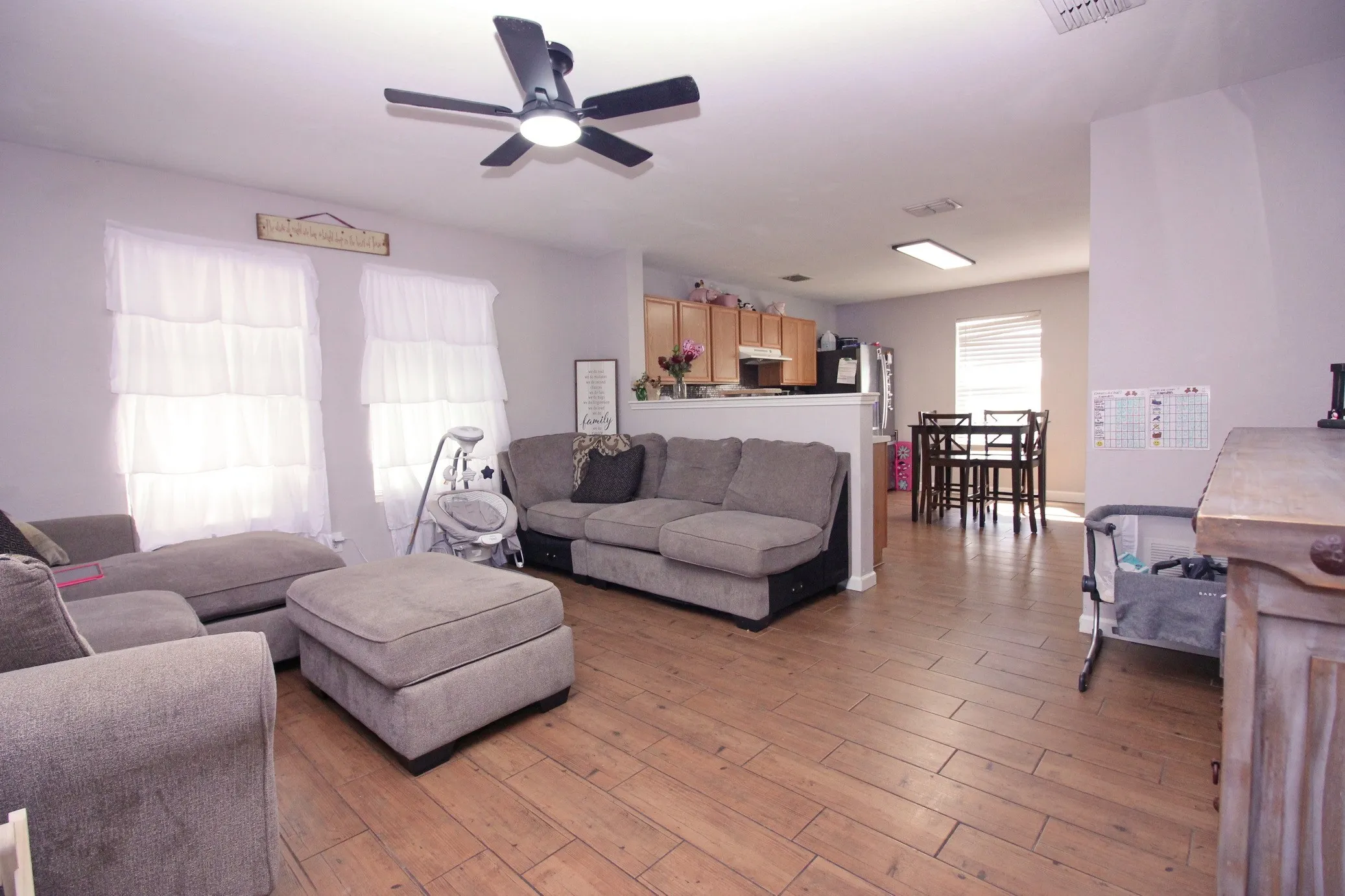 Wood-finish flooring throughout, ceiling fan with integrated lighting, recessed lighting, kitchen featuring wood cabinetry, dining space with window