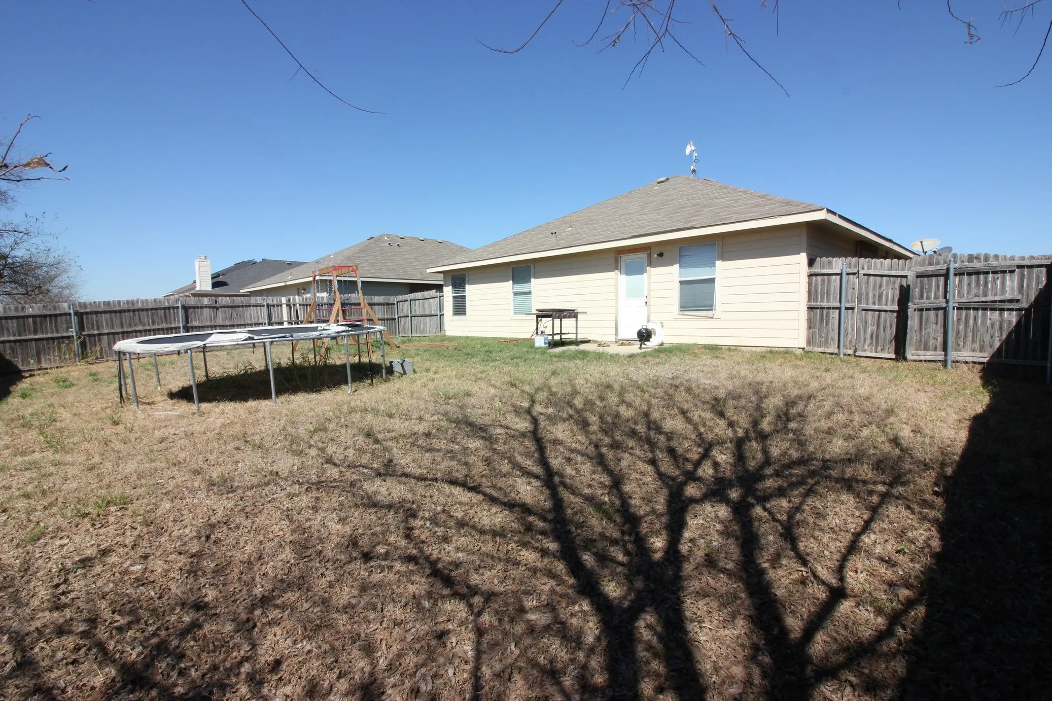 Expansive backyard featuring a wood privacy fence, concrete patio, and neutral-toned siding